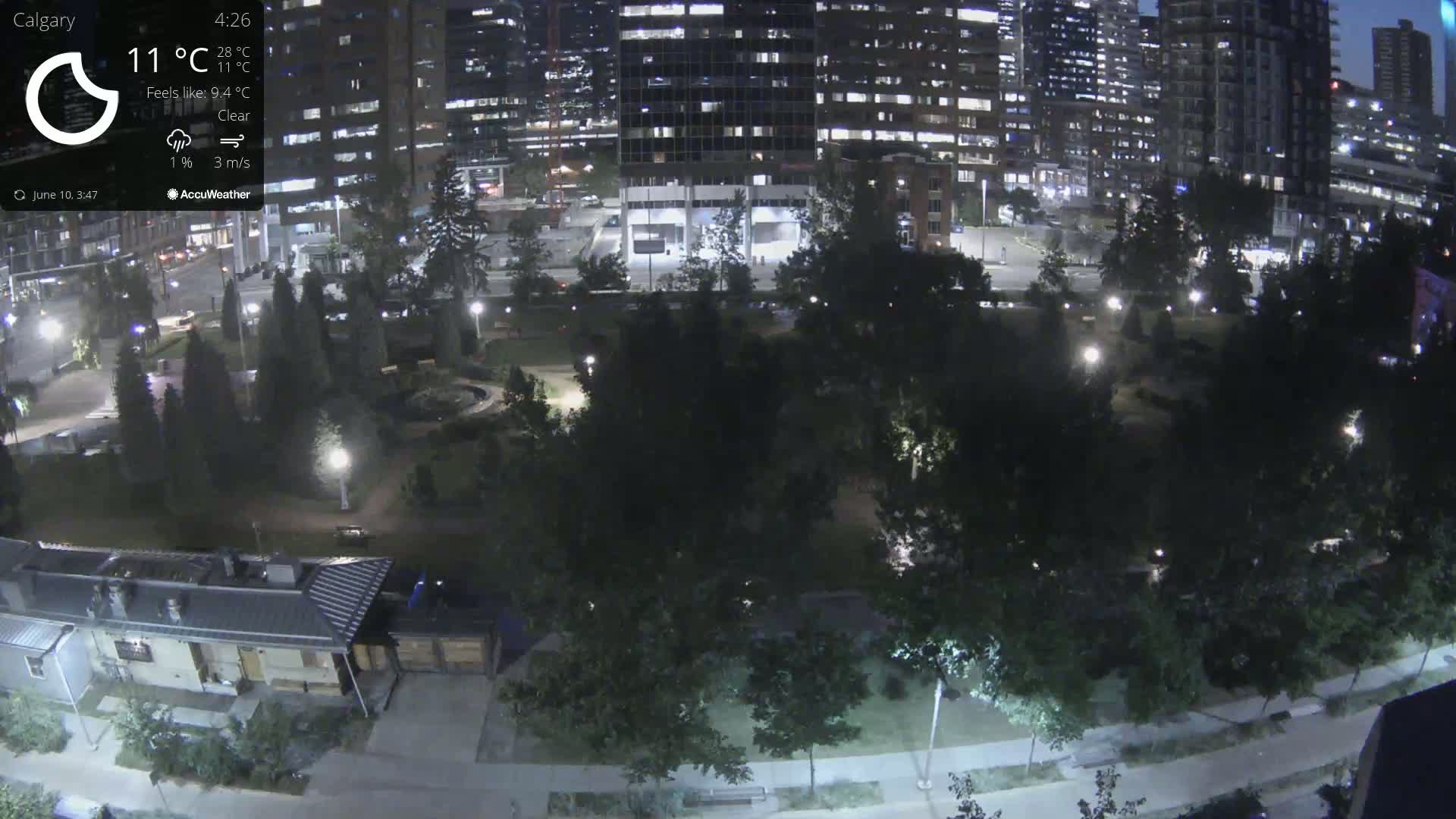 A nighttime aerial view of a park surrounded by city buildings under clear skies.
