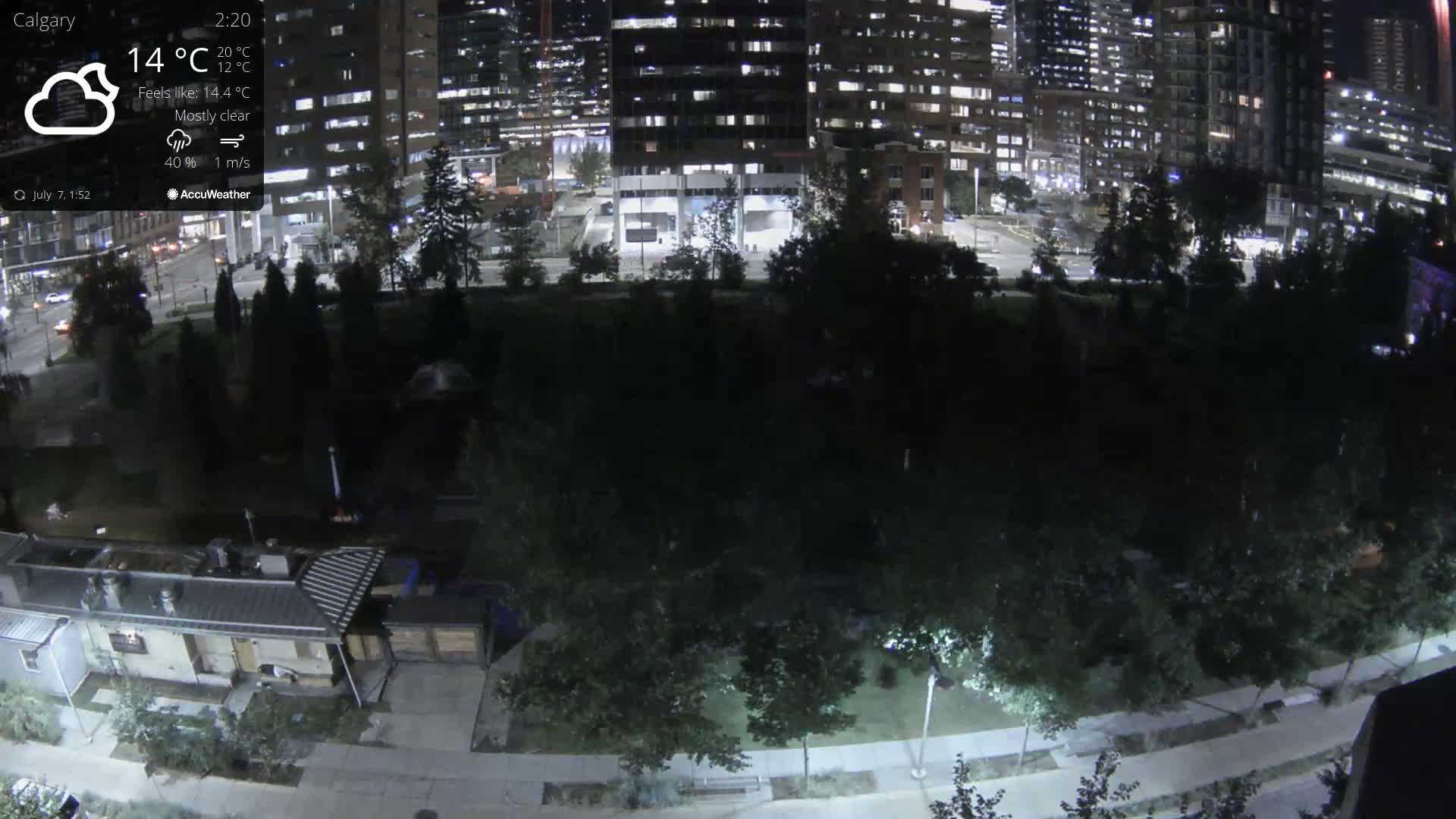 A nighttime aerial view of a city park bordered by illuminated buildings under mostly clear skies.