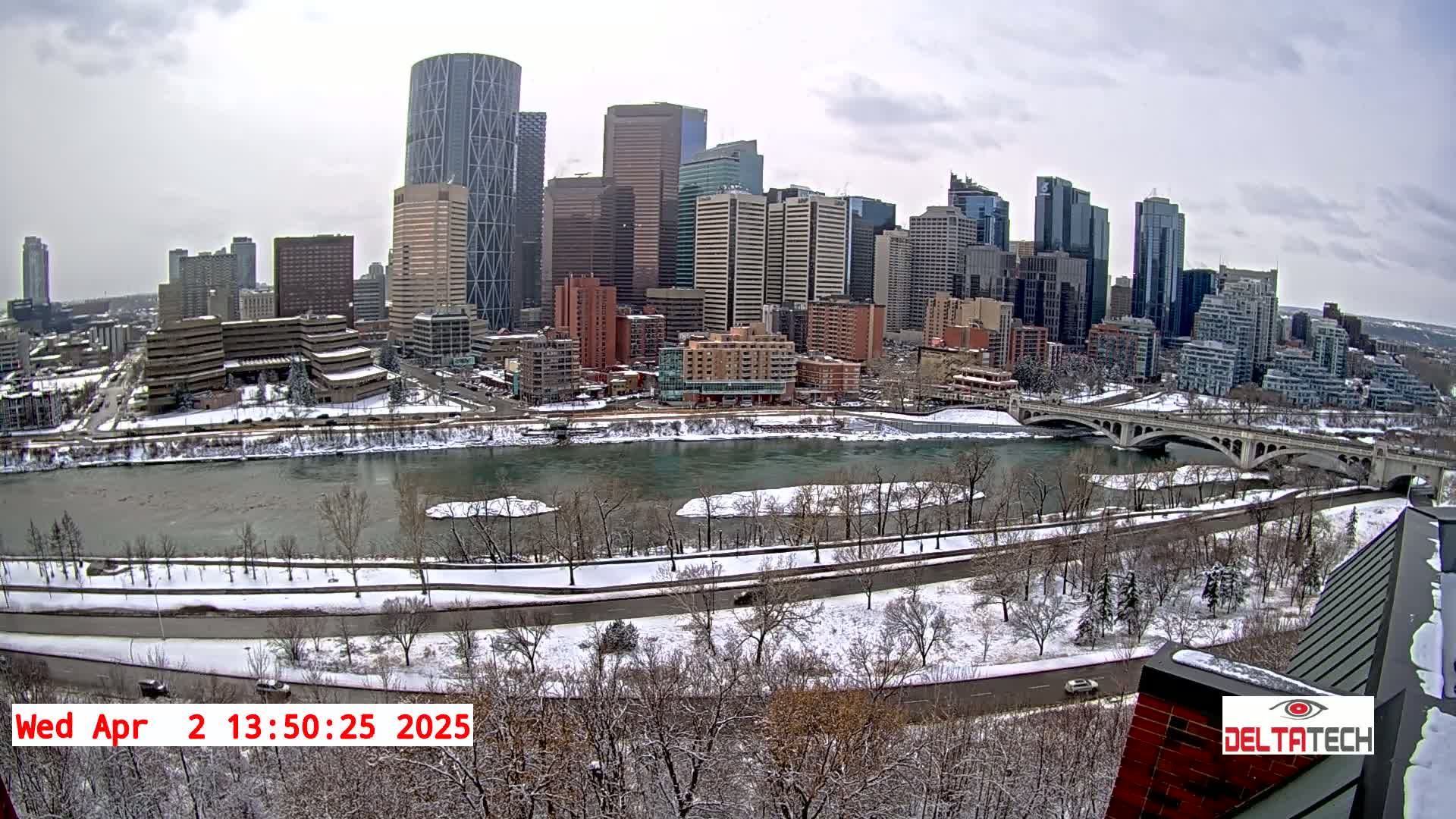 A snow-covered city skyline with a river and bridge is visible, under a cloudy sky.