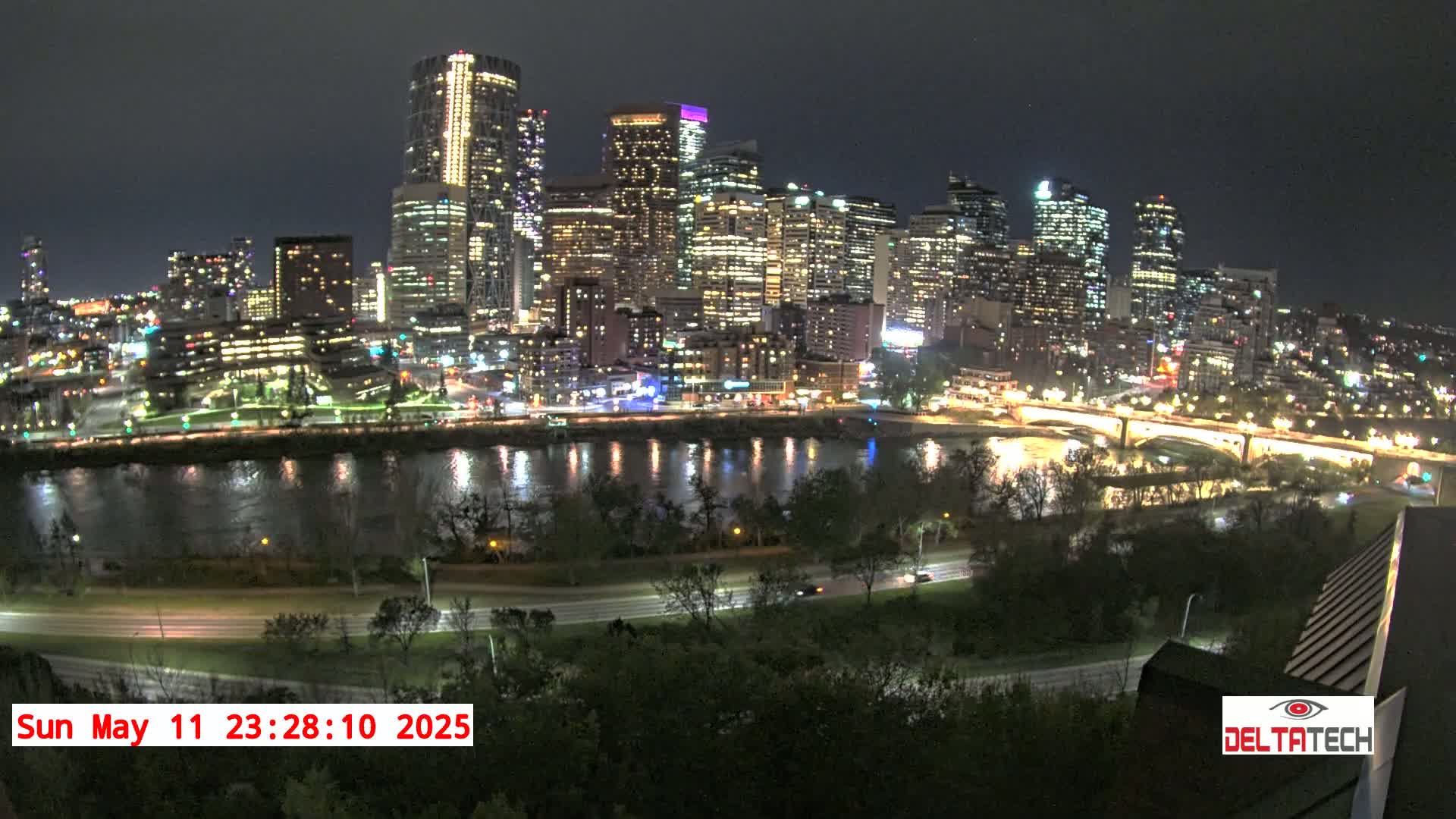A nighttime view of a city skyline across a river, with city lights reflecting on the water.