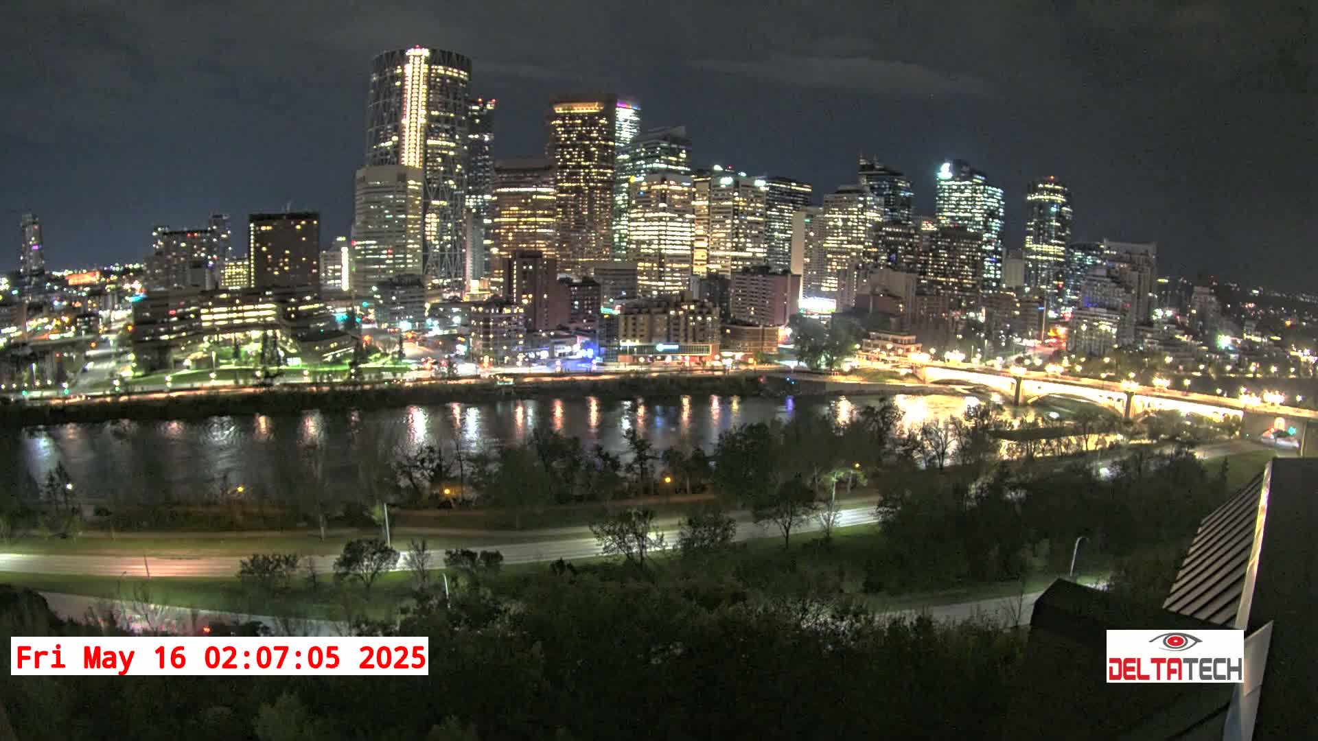 A nighttime view of a city skyline illuminated with lights across a river, under a clear sky.