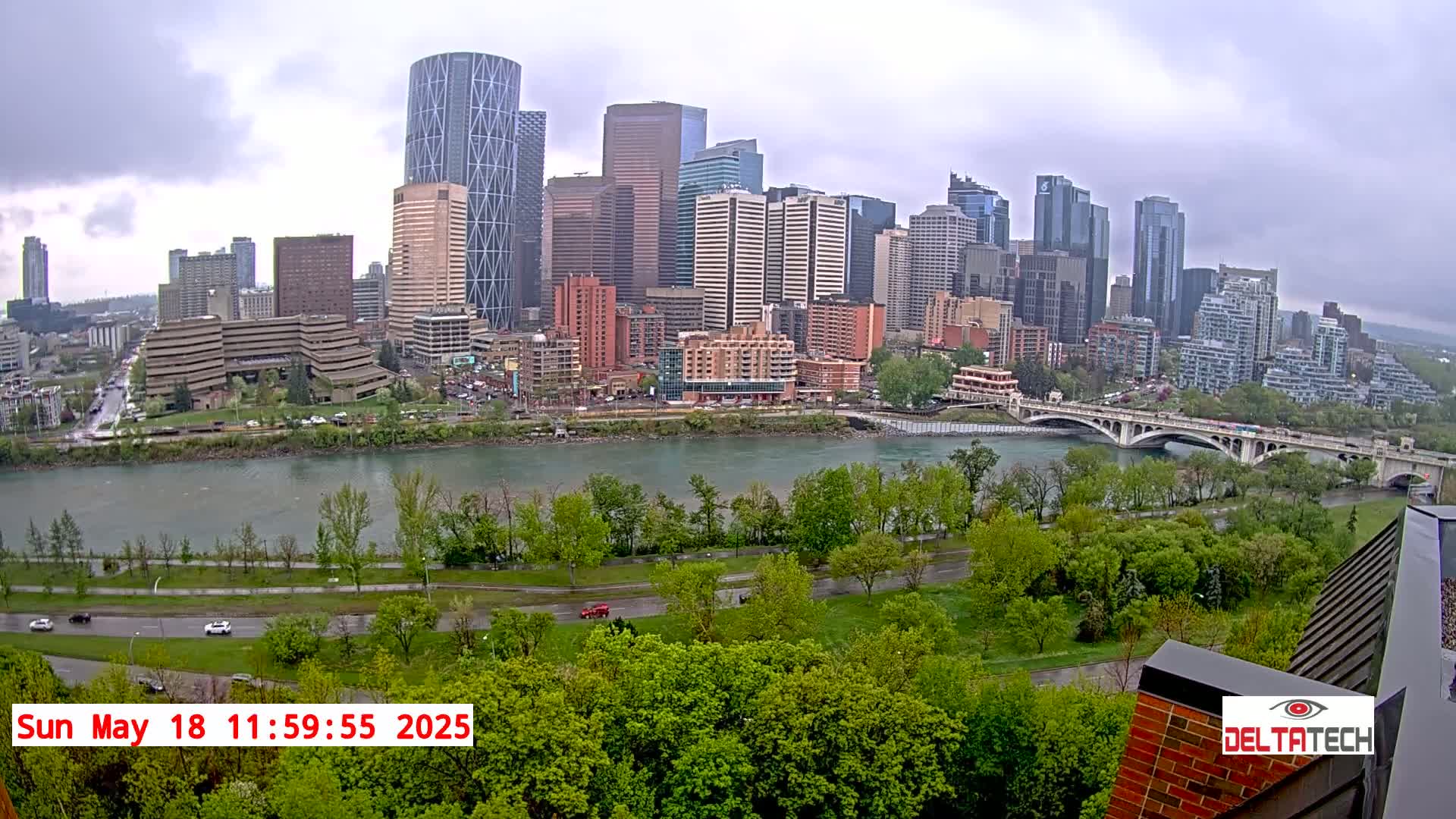 A city skyline with numerous high-rise buildings is visible across a river on an overcast day.