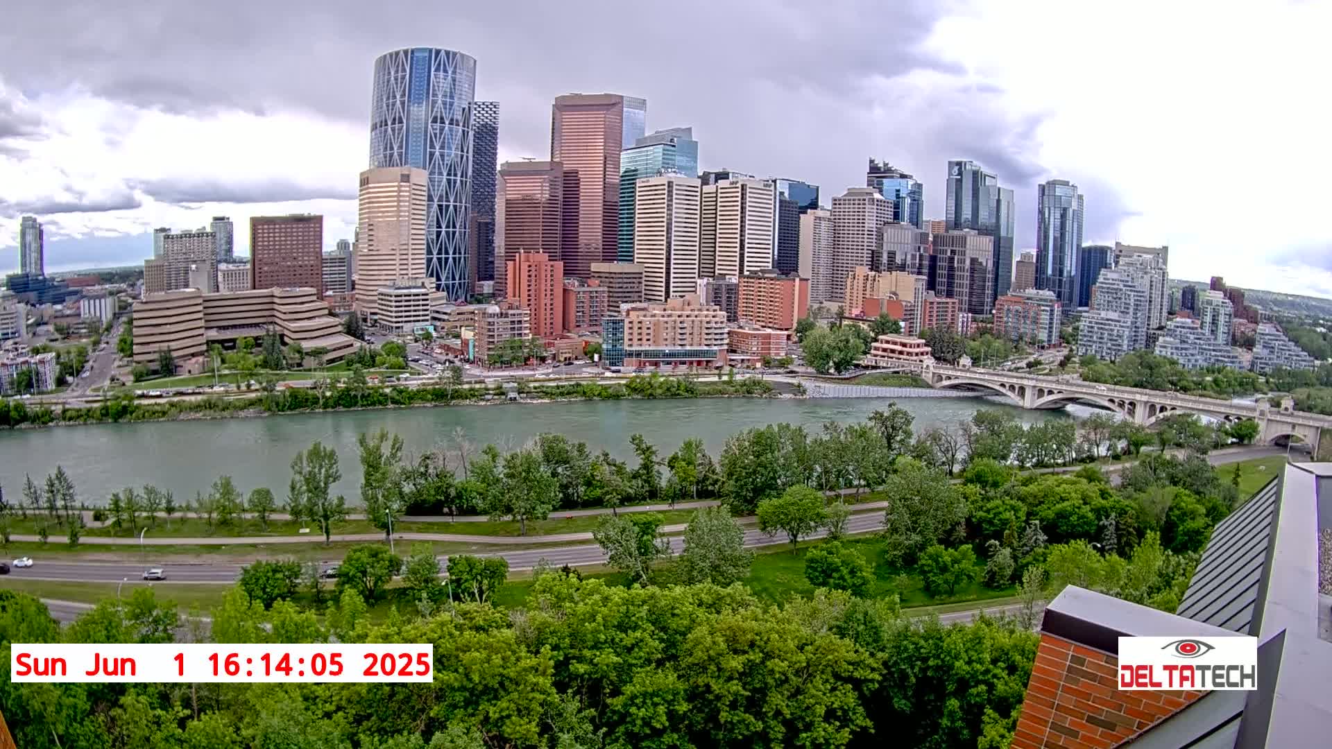 A city skyline with numerous skyscrapers is visible across a wide river, under a partly cloudy sky.