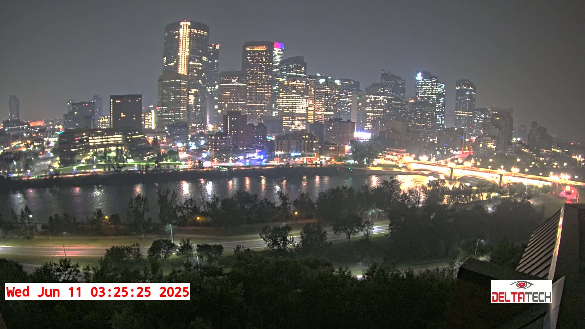 A nighttime view of a city skyline across a river, with hazy or smoky atmospheric conditions.