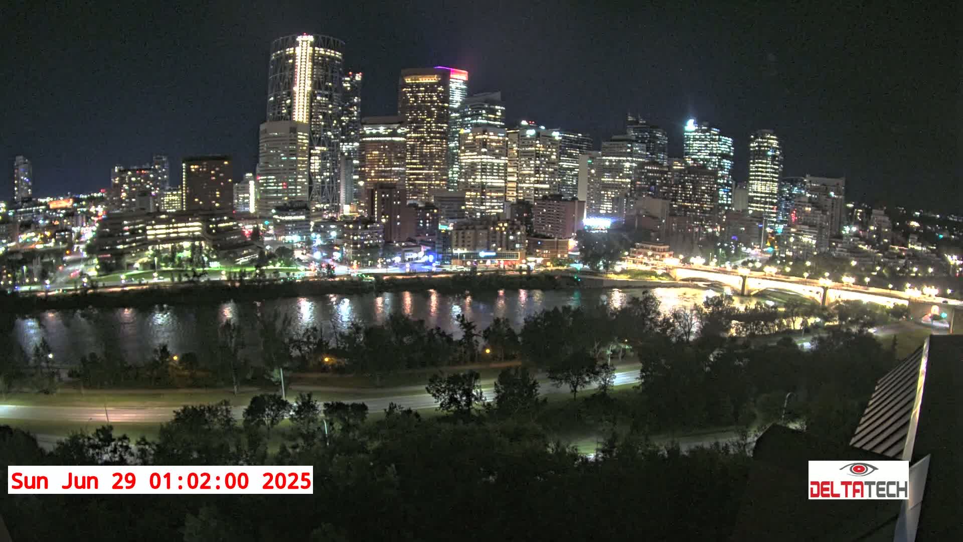 A nighttime view of a city skyline illuminated with lights across a river, under a clear sky.