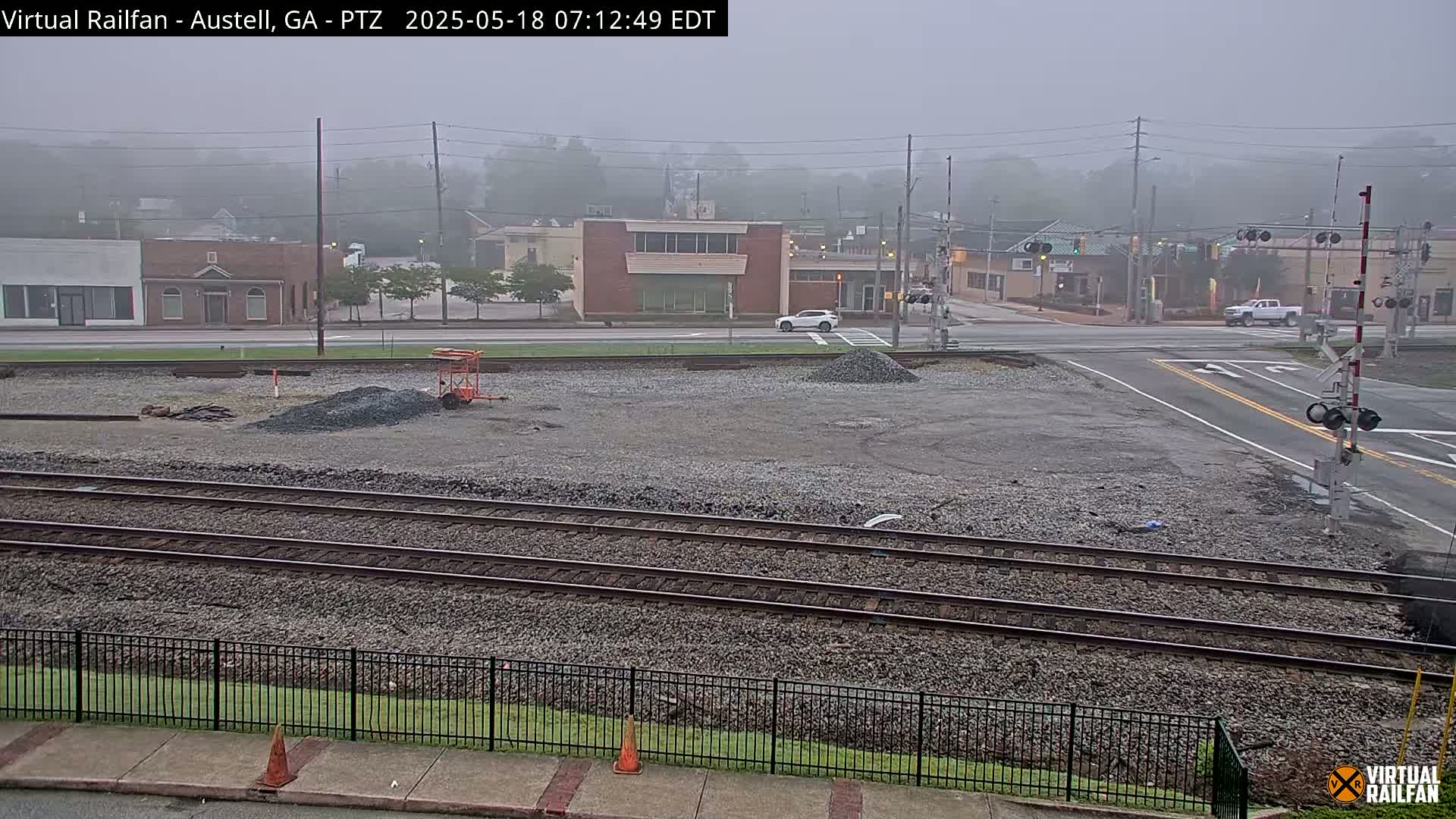 A foggy view of a railway crossing near a town intersection, with construction materials and equipment visible in the foreground.