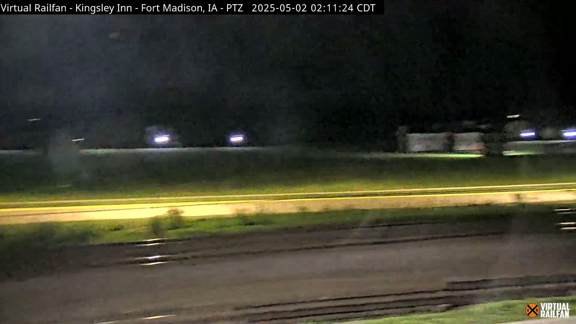At night, a train passes by a highway.
