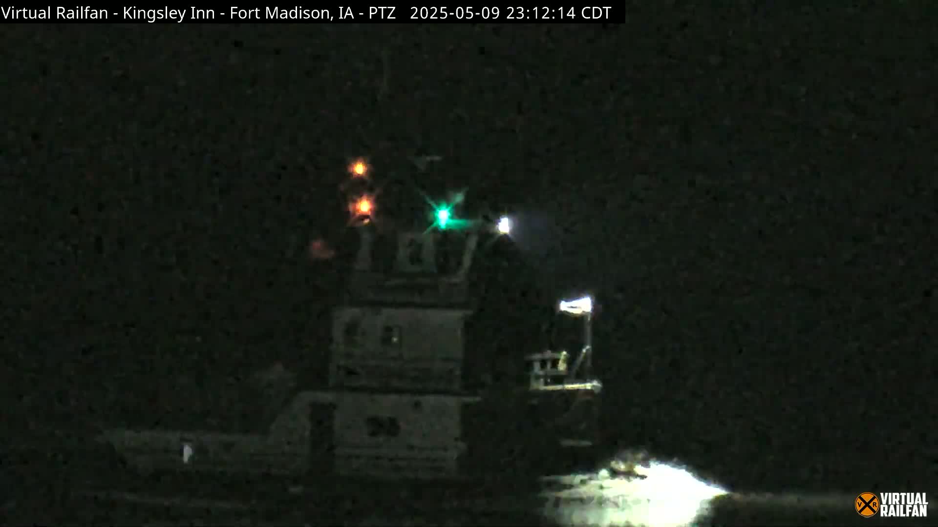 A tugboat with illuminated lights is visible at night on a body of water.