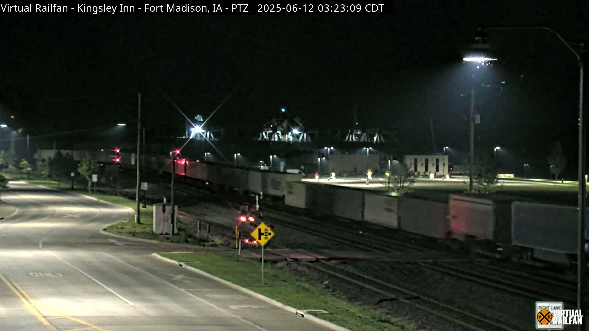 A long freight train passes under a bridge at night.