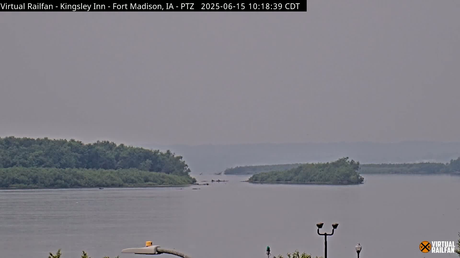 A hazy view of a wide river with wooded islands in the distance.