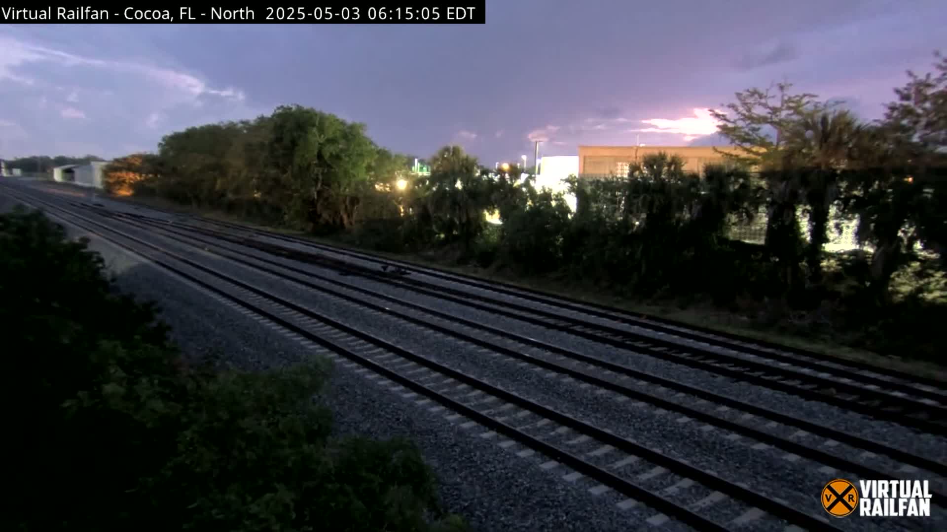 Multiple sets of train tracks stretch into the distance under a twilight sky with a hint of pink and purple clouds.