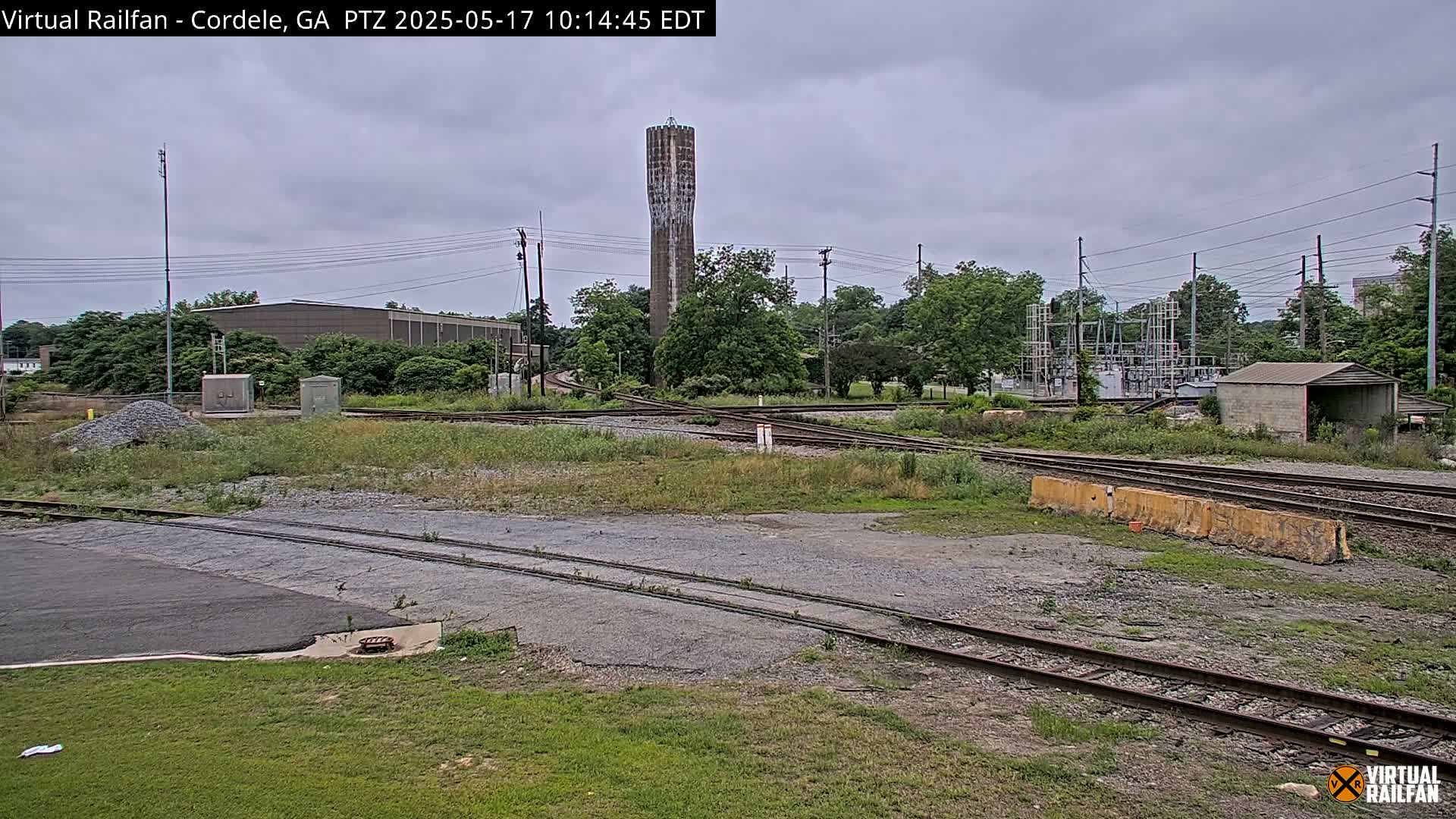 A view of railroad tracks and a water tower under an overcast sky.