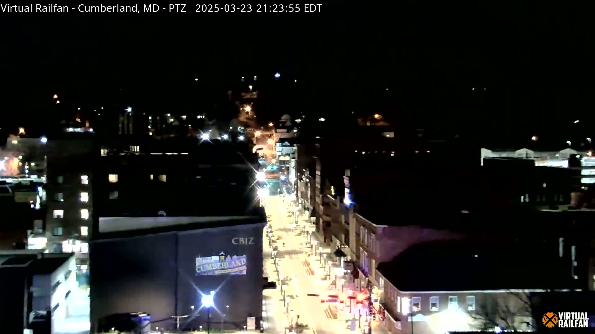 A nighttime, high-angle view of a city street with illuminated buildings and vehicles.