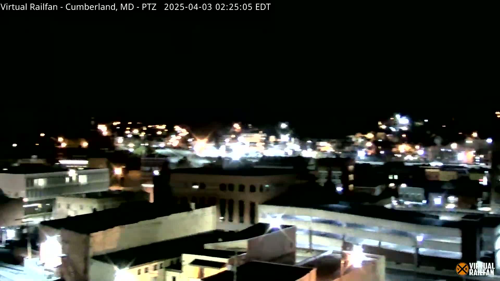 A nighttime, high-angle view of a city with numerous illuminated buildings and streets.