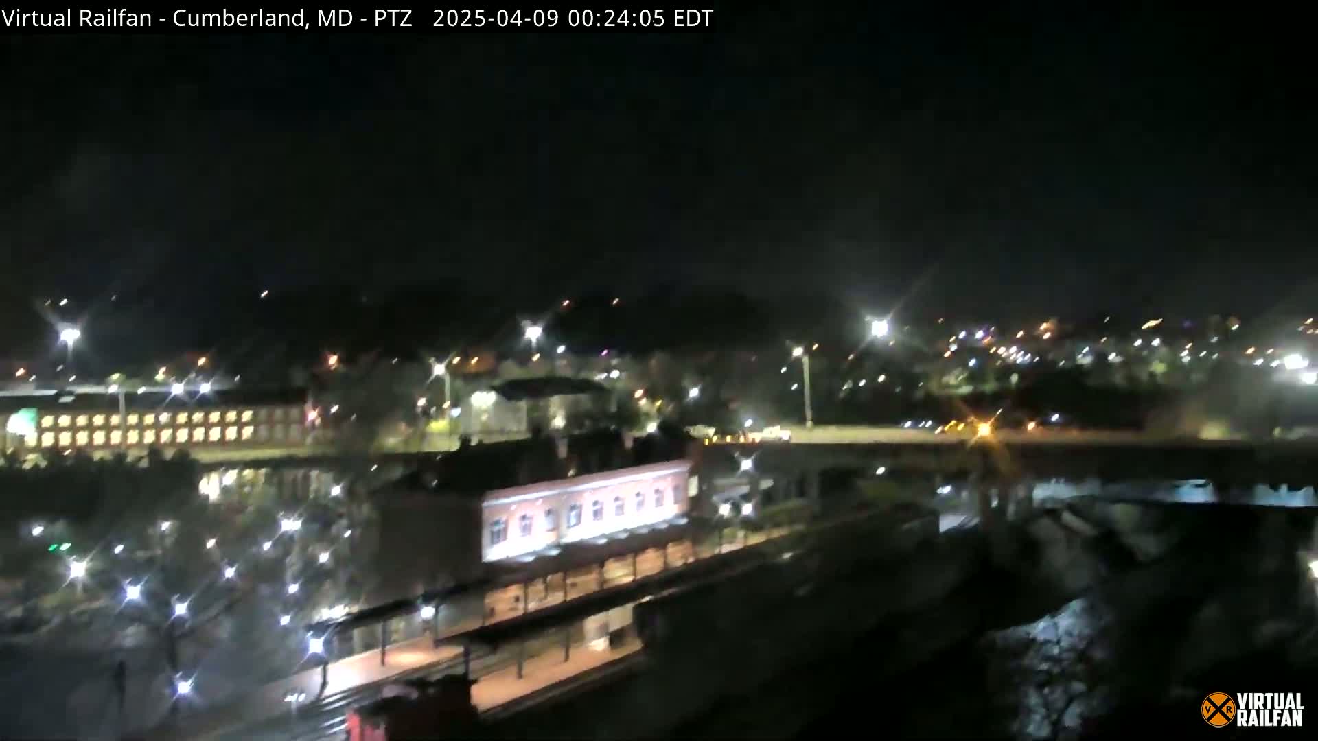 A nighttime view of a train station and surrounding city illuminated by streetlights.