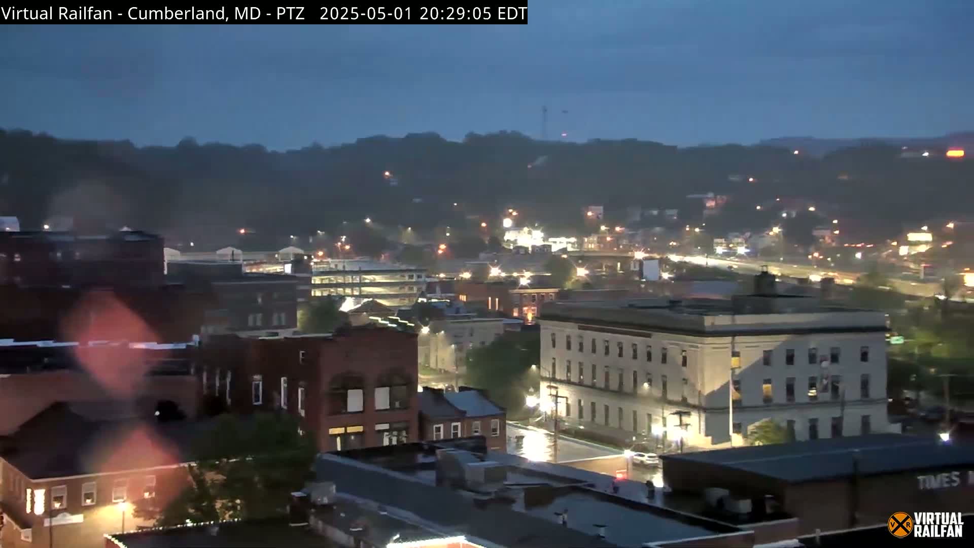 A nighttime view of a city nestled in hills under a dusky sky.
