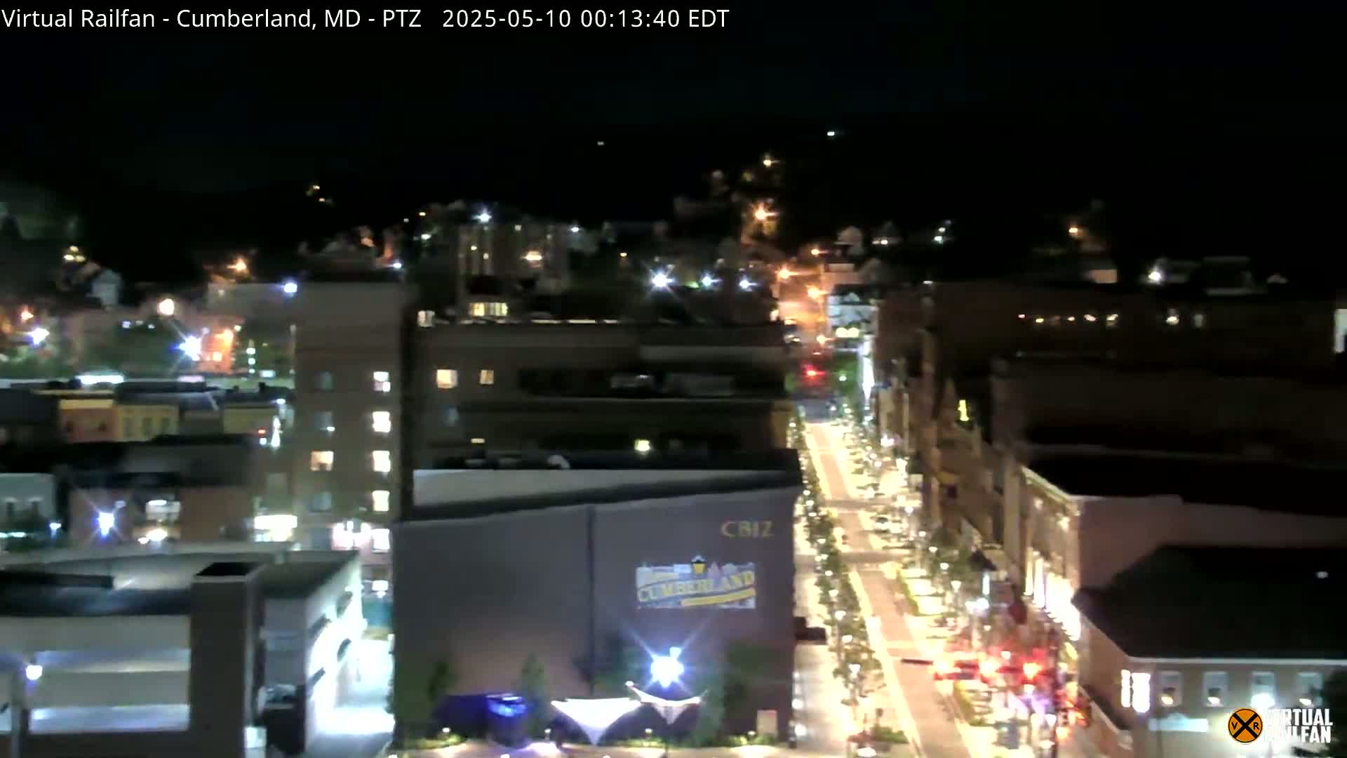 A nighttime, high-angle view of a city street with illuminated buildings and vehicles.