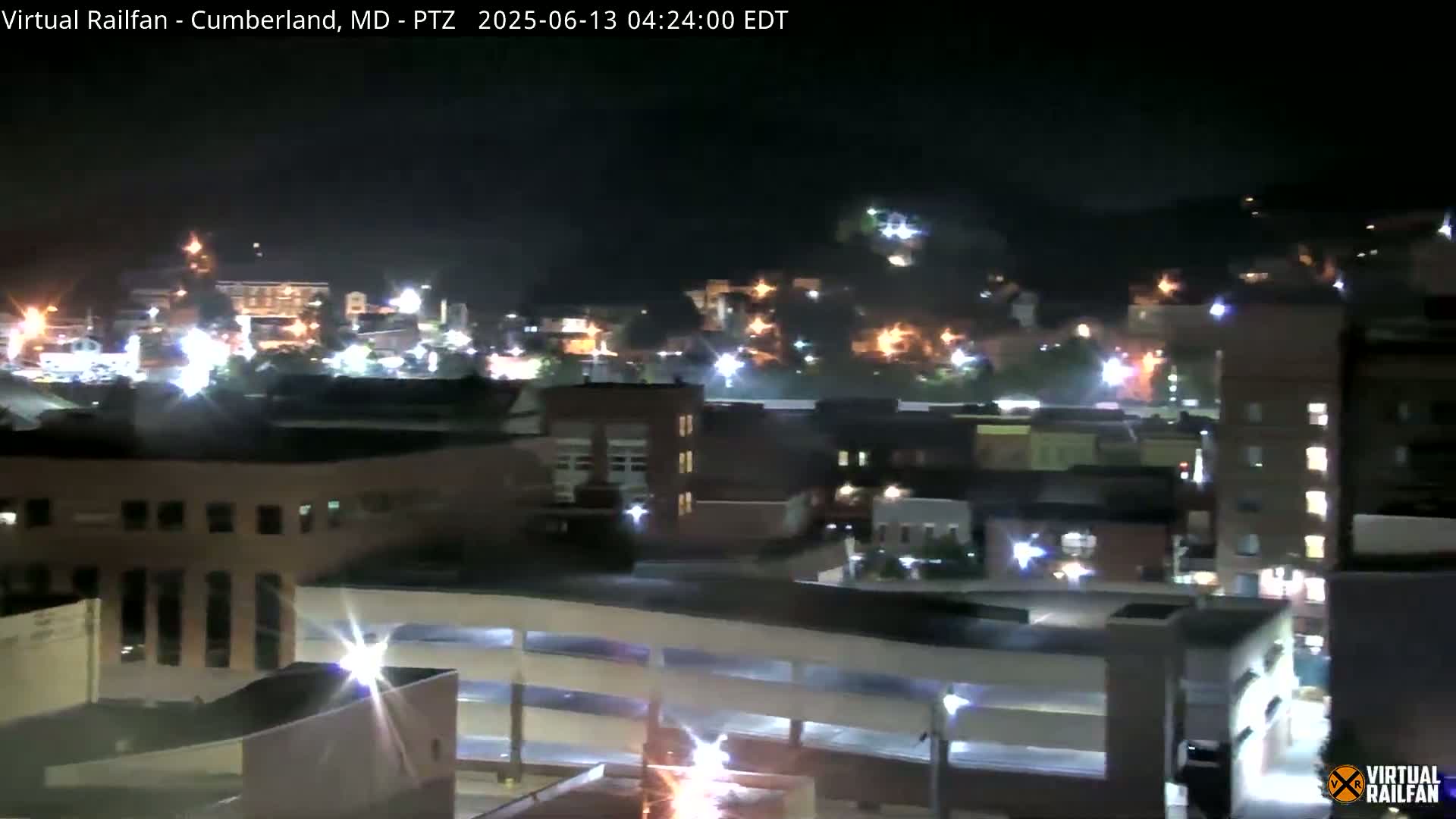 A nighttime, high-angle view shows a city illuminated by streetlights and building lights.