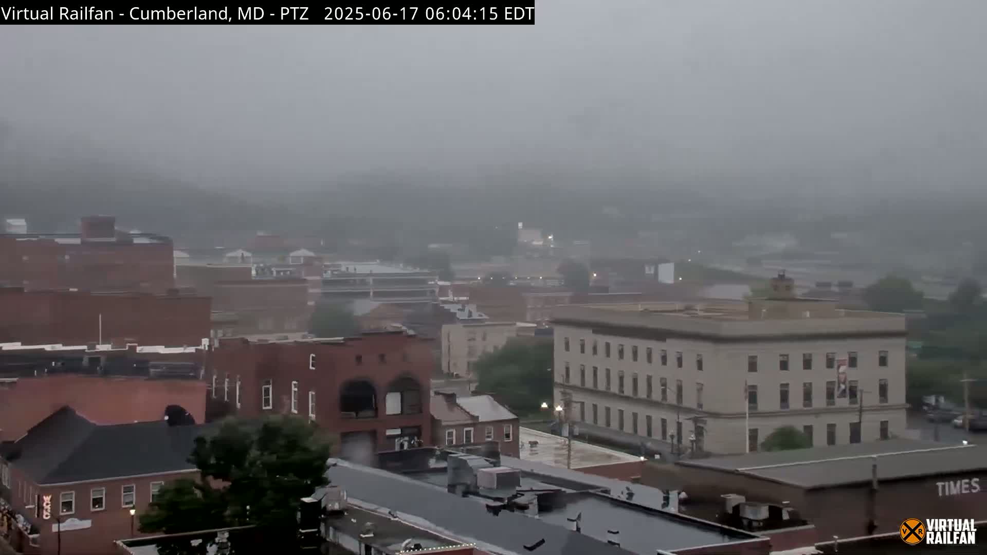 A hazy, rainy view of a town with brick buildings and trees.
