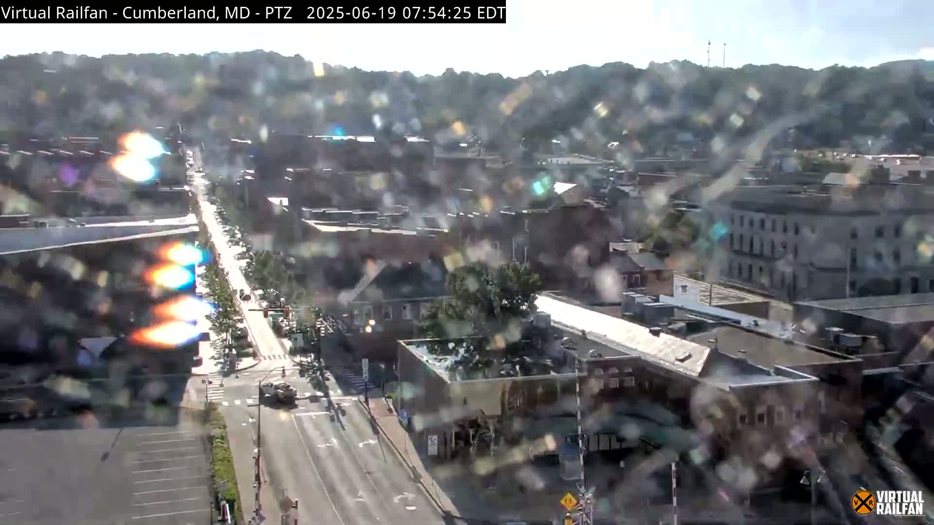A partly sunny, hazy view of a city street scene with buildings and cars, seen from a high vantage point.
