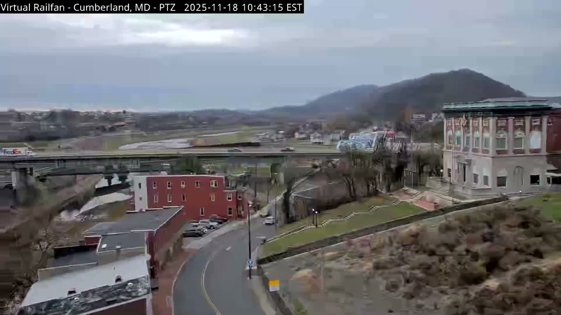 A brightly lit building stands at night among other dark structures and trees under a dark sky.