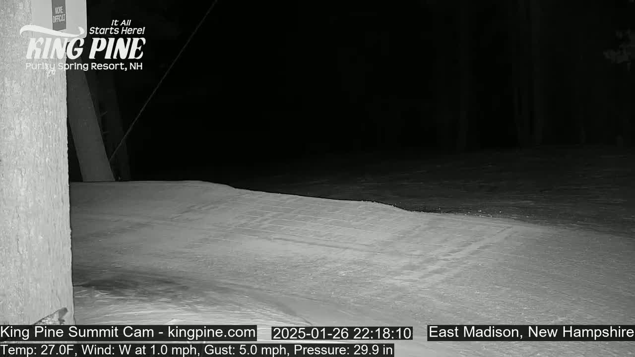 A snow-covered area is seen at night, illuminated by a light source, with a gentle west wind.