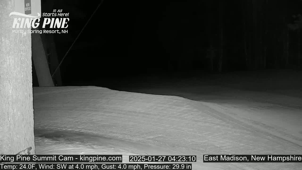 A nighttime view of a snow-covered slope under a dark sky.