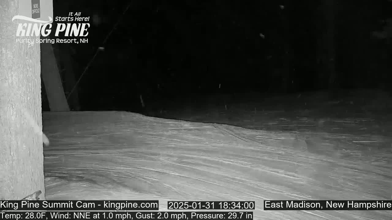 A nighttime snow scene shows a snow-covered slope with light snowfall.