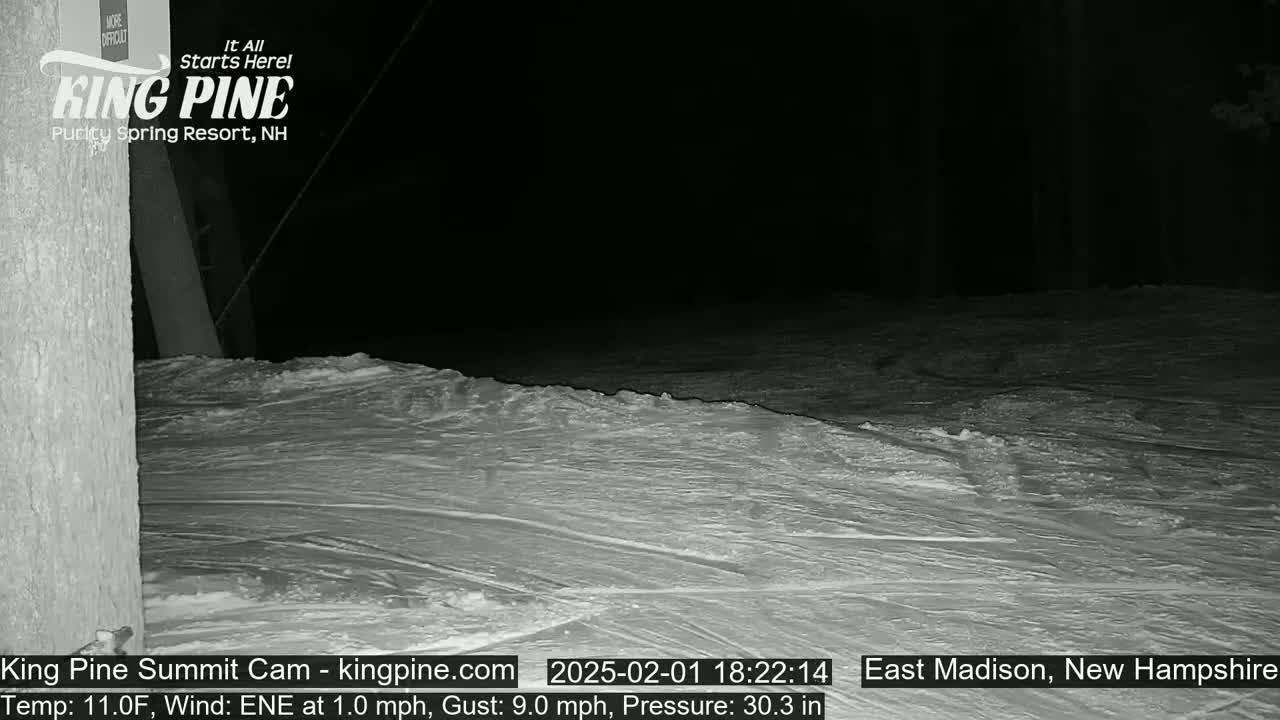 A nighttime view of a snow-covered slope under a dark sky.