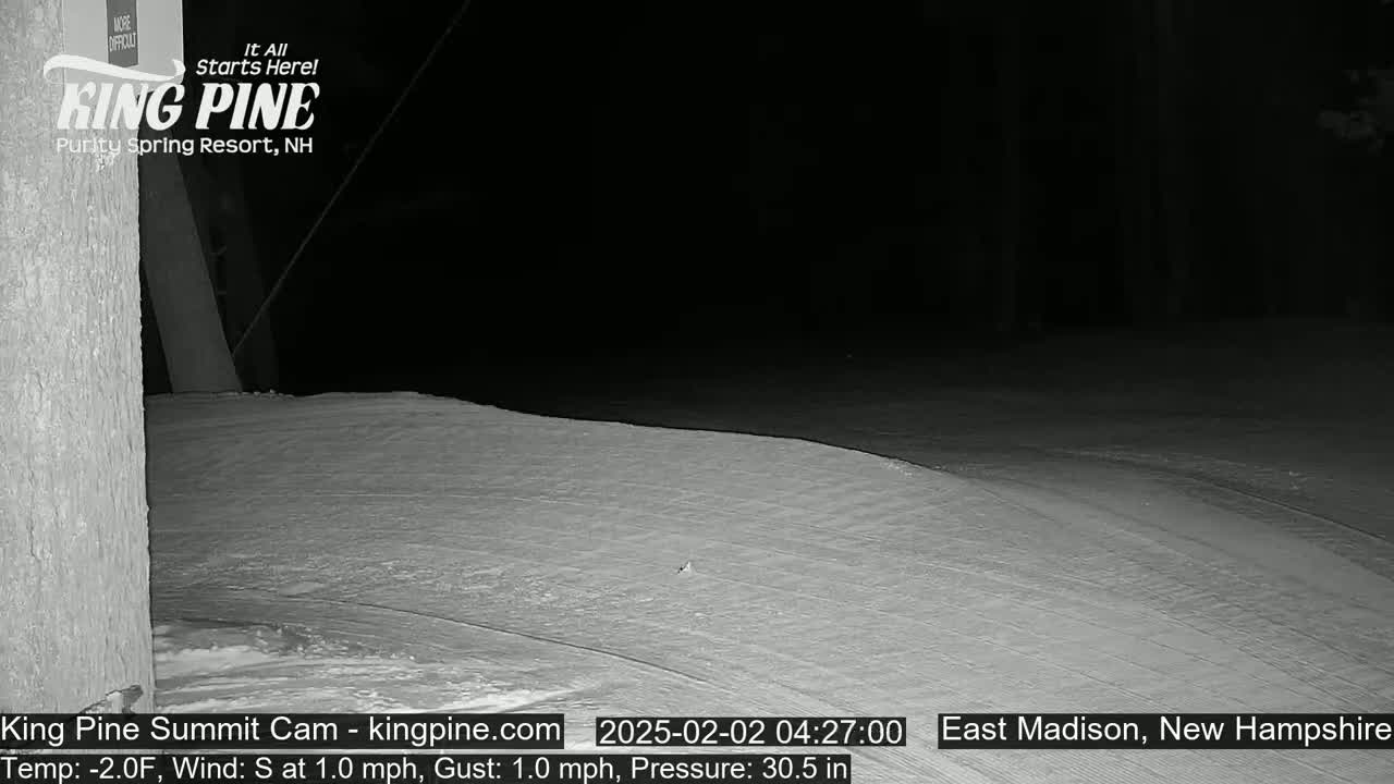 A snow-covered slope is visible at night under dark conditions.