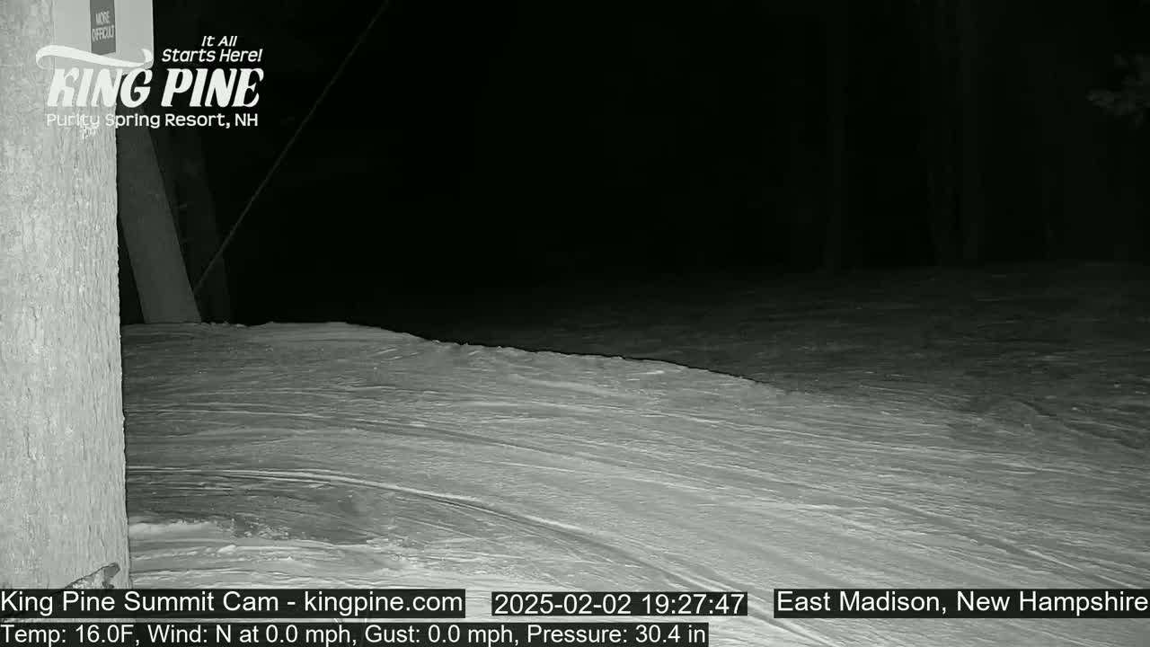 A nighttime snow-covered slope is seen under a dark sky.