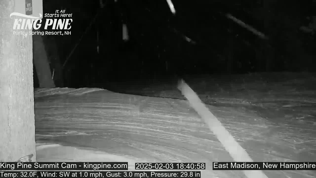 A nighttime snow scene shows a snow-covered surface with light snowfall.