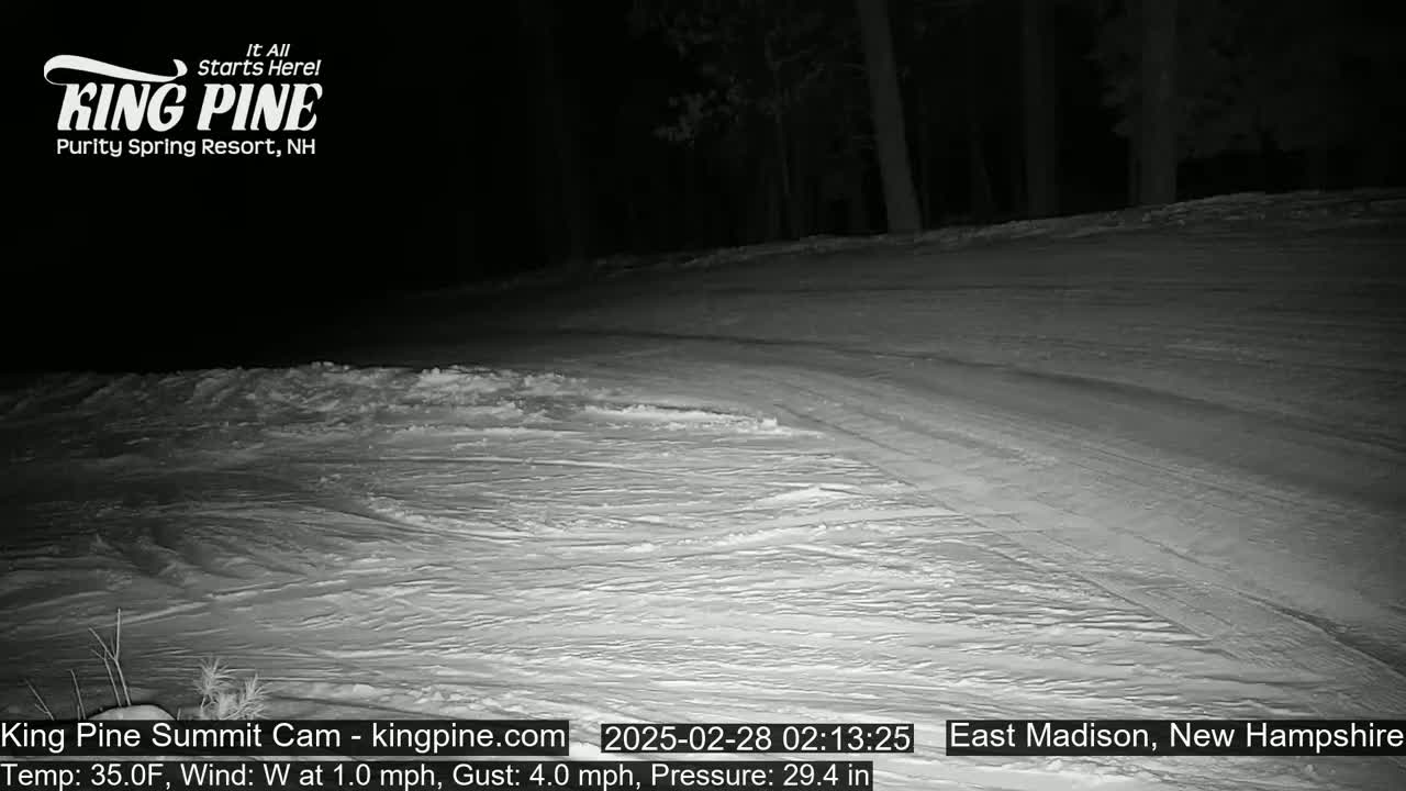 A snow-covered slope at night, under a dark sky with a west wind.