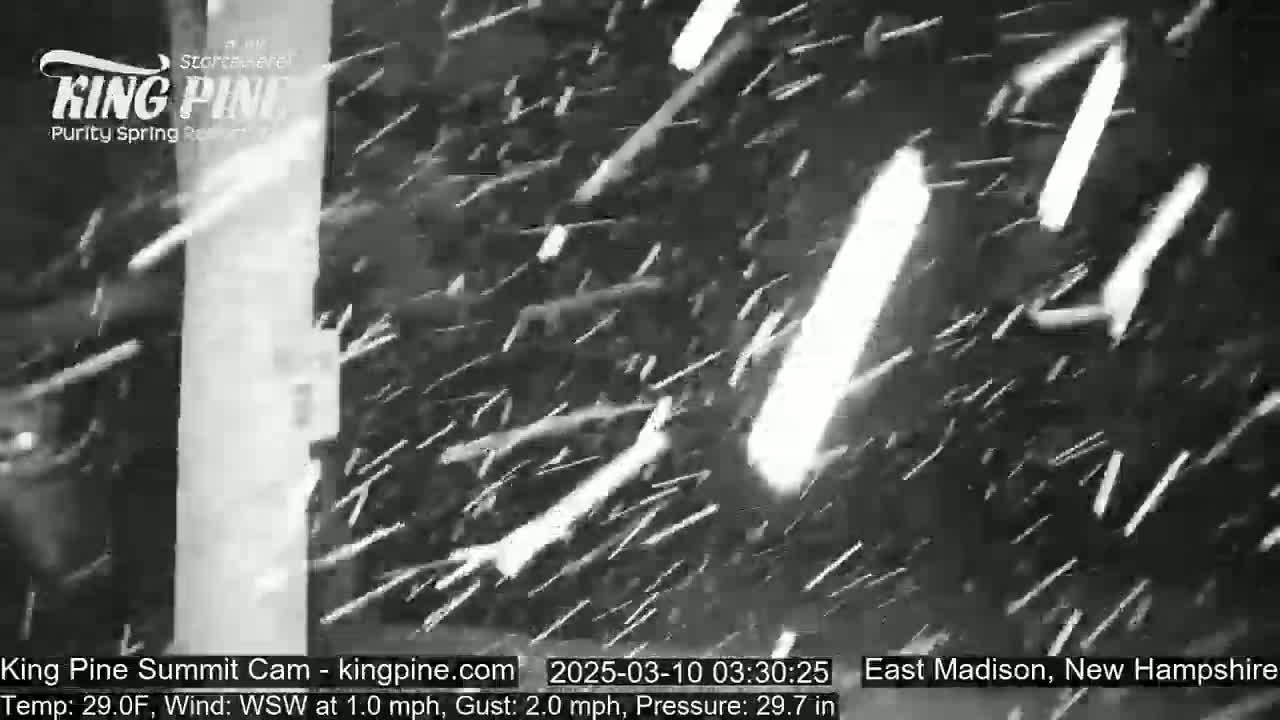 Snow is falling heavily in a dark, outdoor scene.