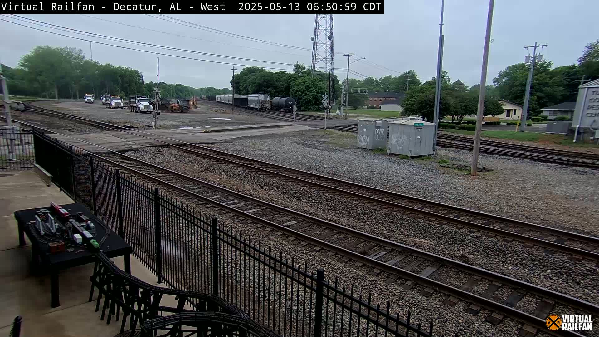 A view of railroad tracks and several pieces of construction equipment under an overcast sky.