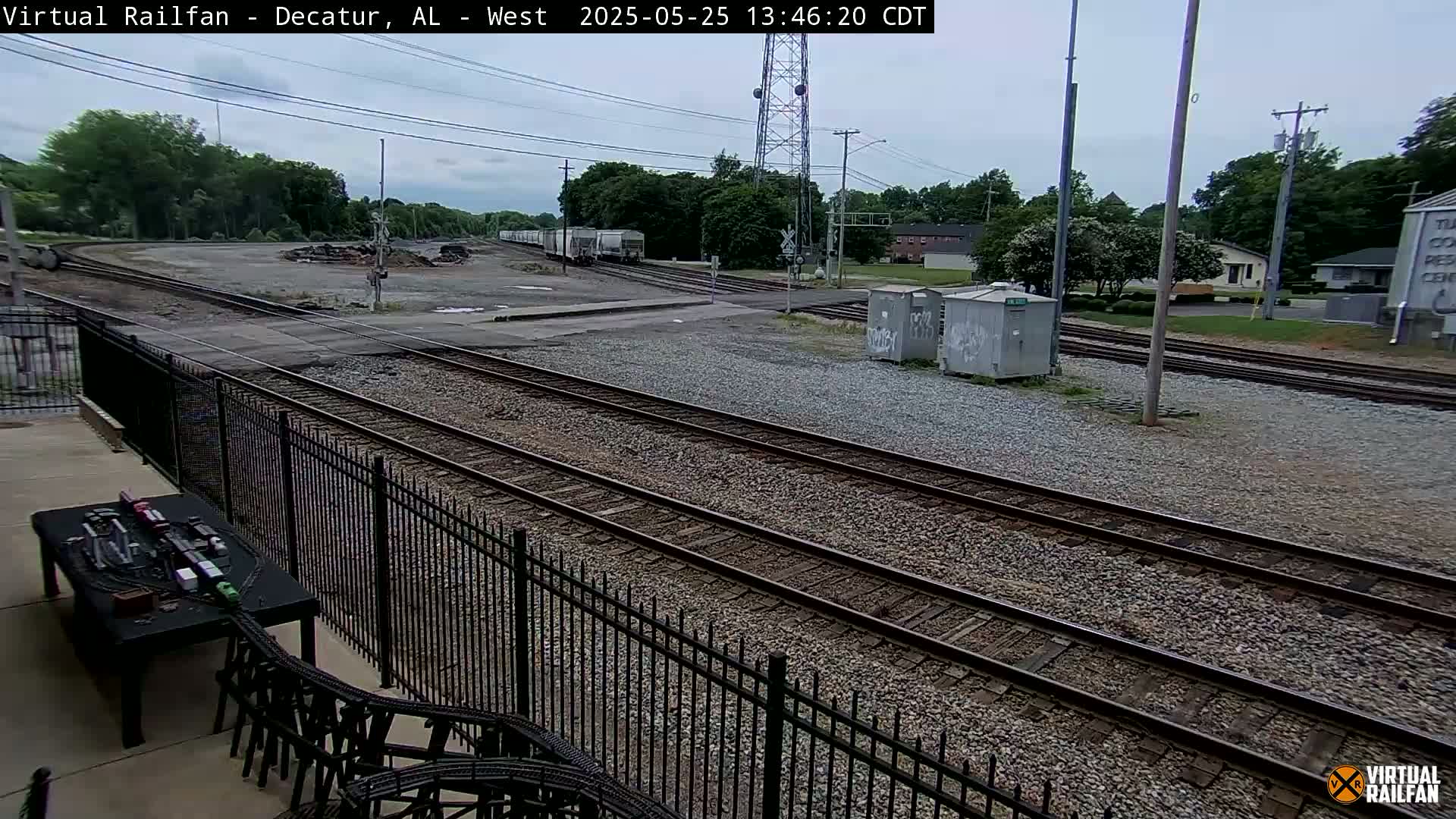 A view of train tracks and rail yards on an overcast day, with some freight cars visible in the distance.