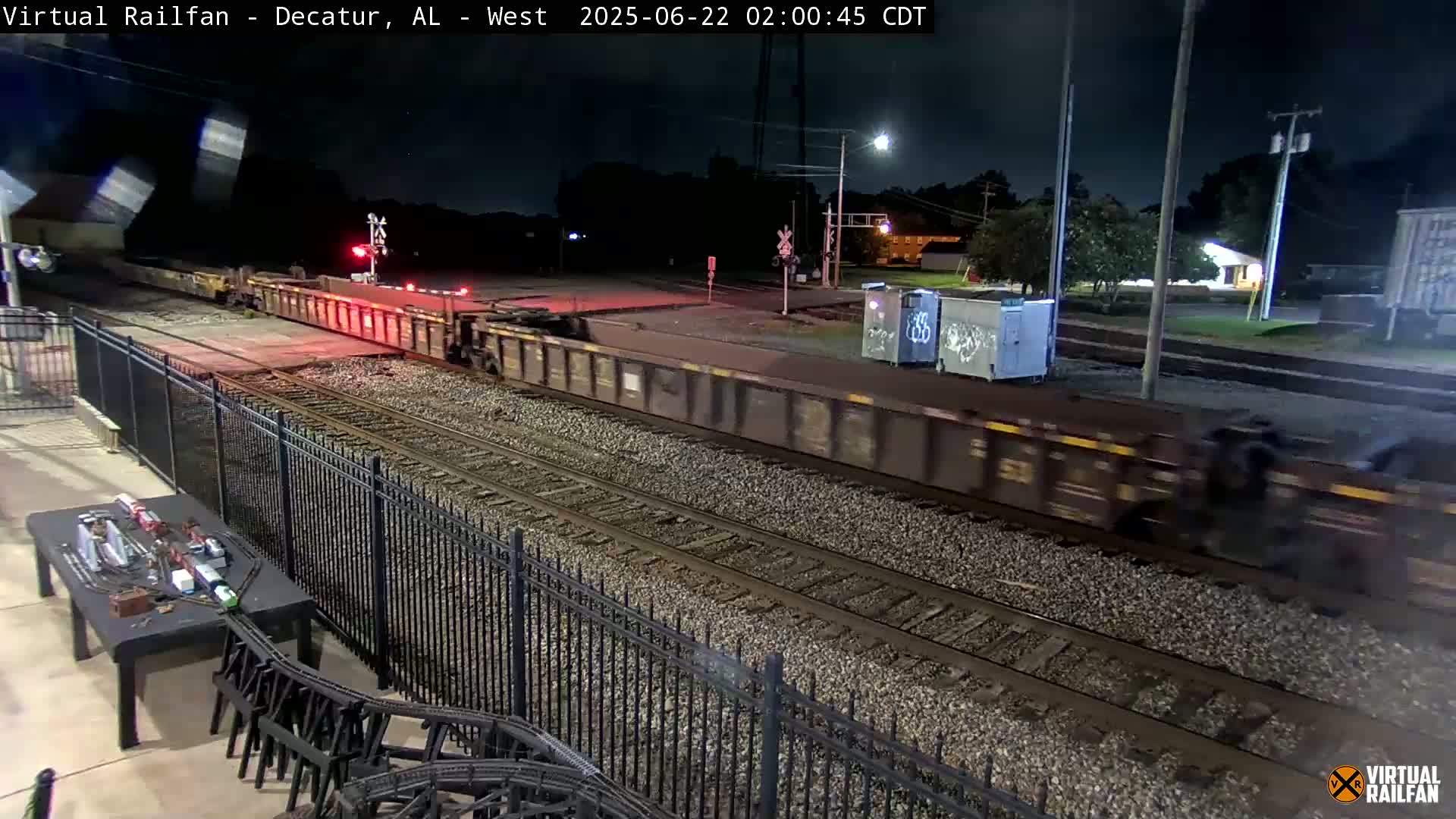 A long freight train moves through a rail yard at night under clear skies.