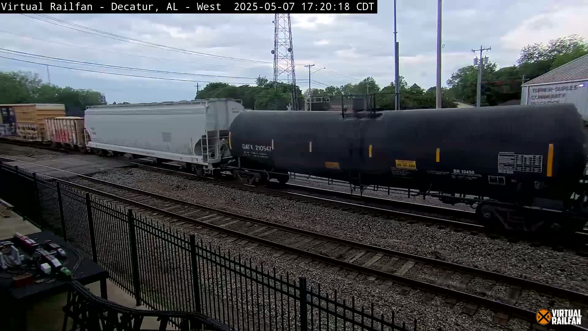 A freight train, consisting of several boxcars and tank cars, passes by under an overcast sky.