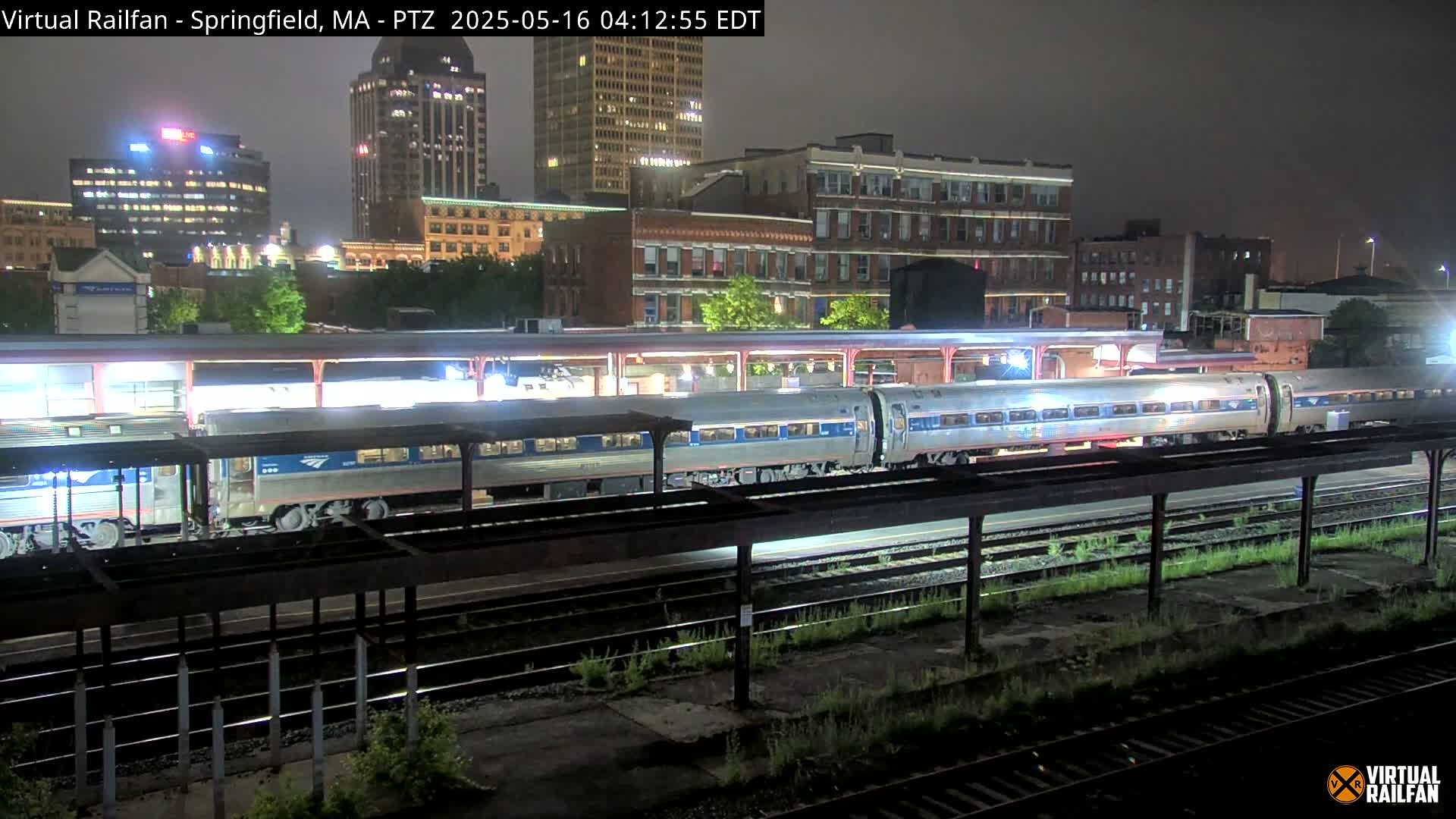A long passenger train is at a station at night under a dark sky.
