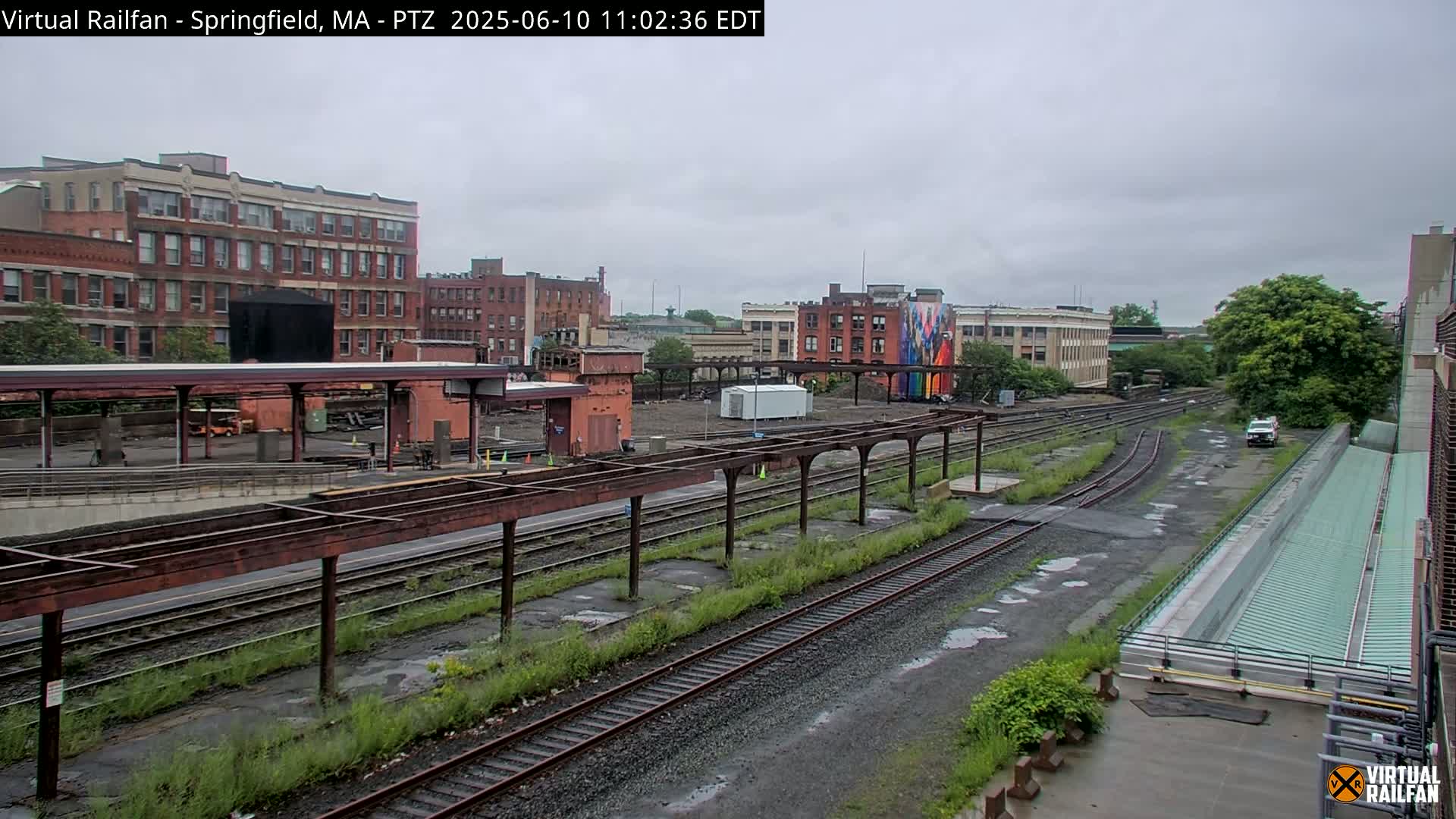 A view of railroad tracks and industrial buildings on an overcast day.