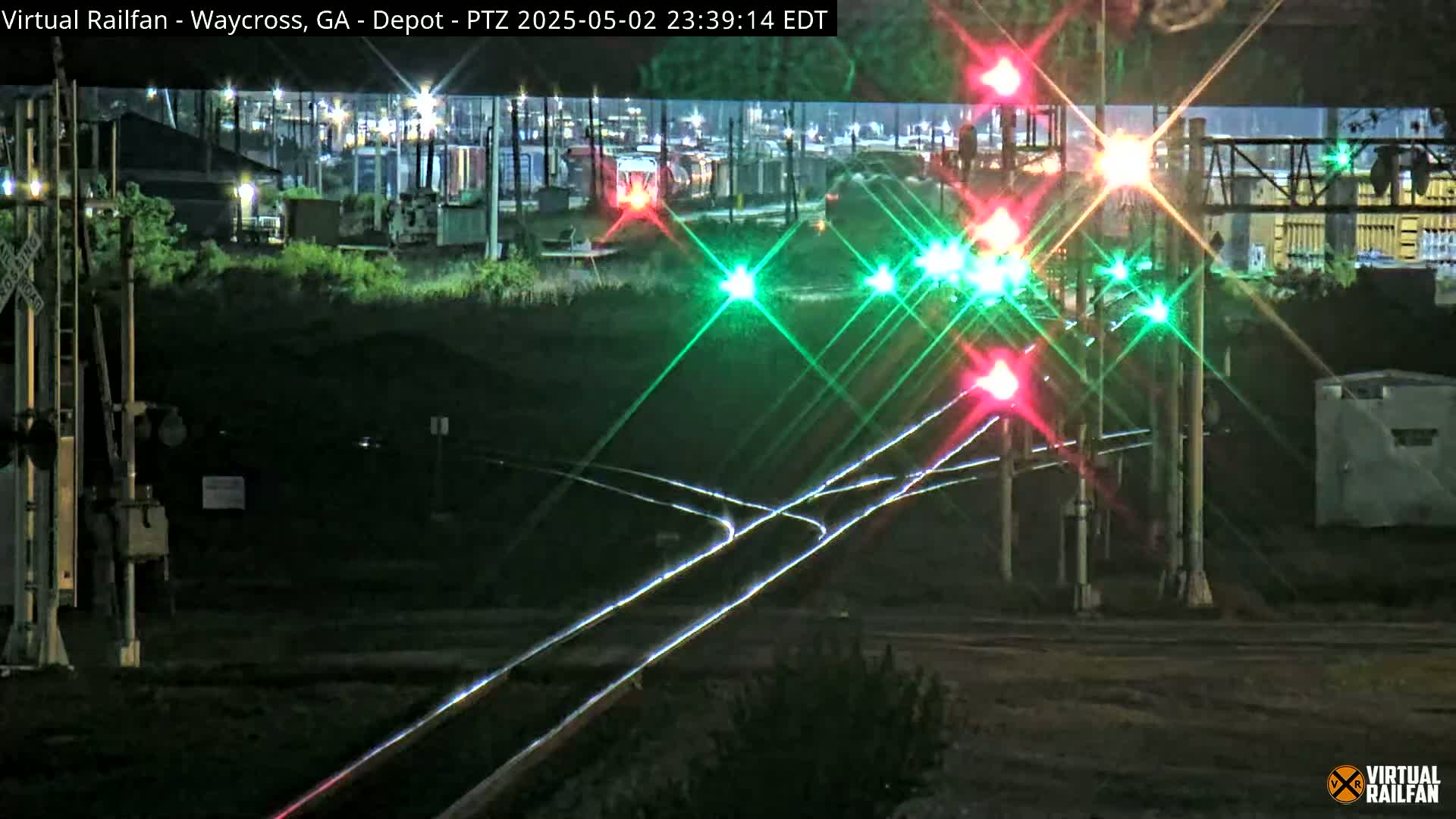 At night, a train passes through a railroad crossing with illuminated signals.