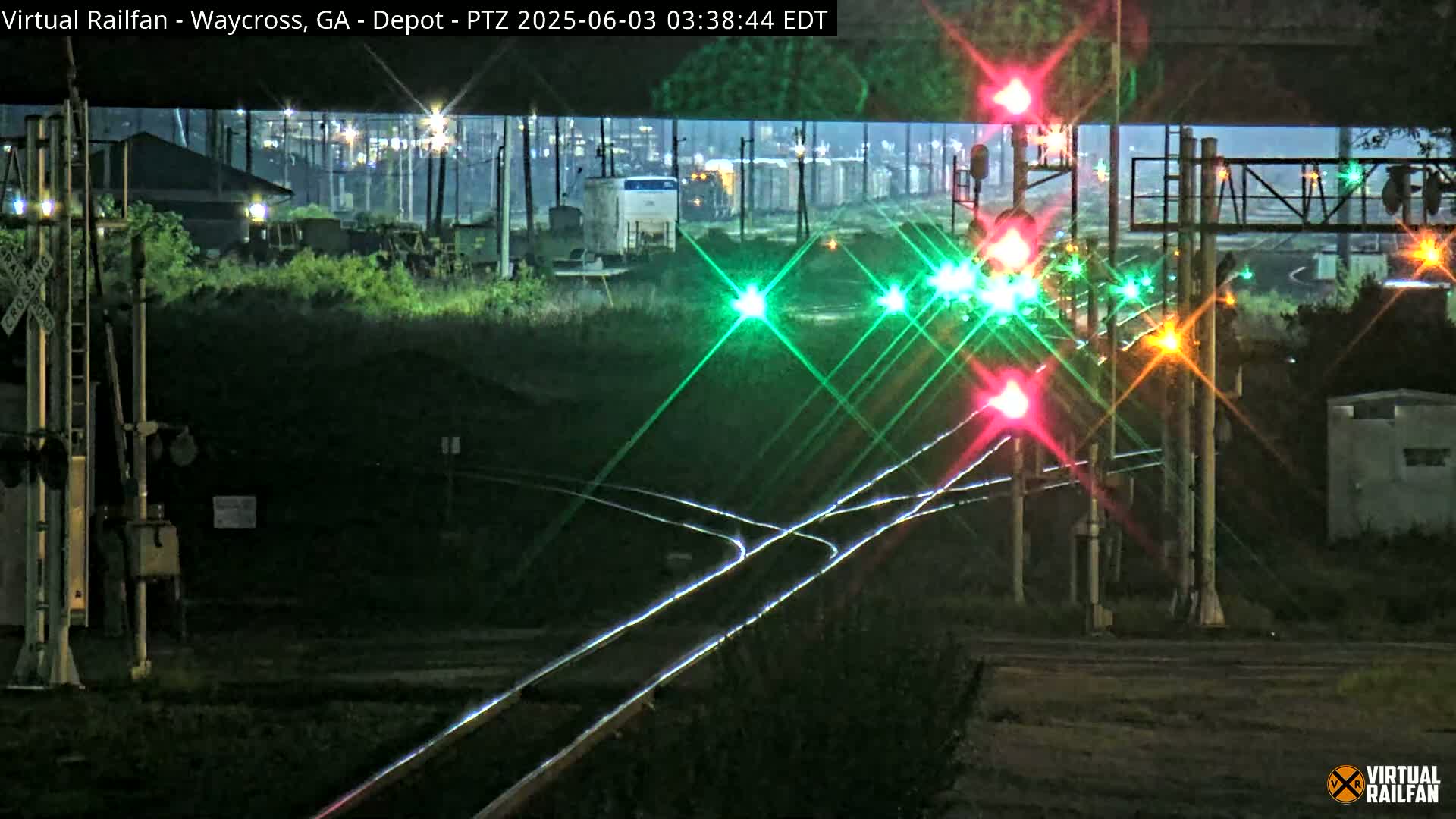 At night, a train passes through a railroad crossing with illuminated signals.