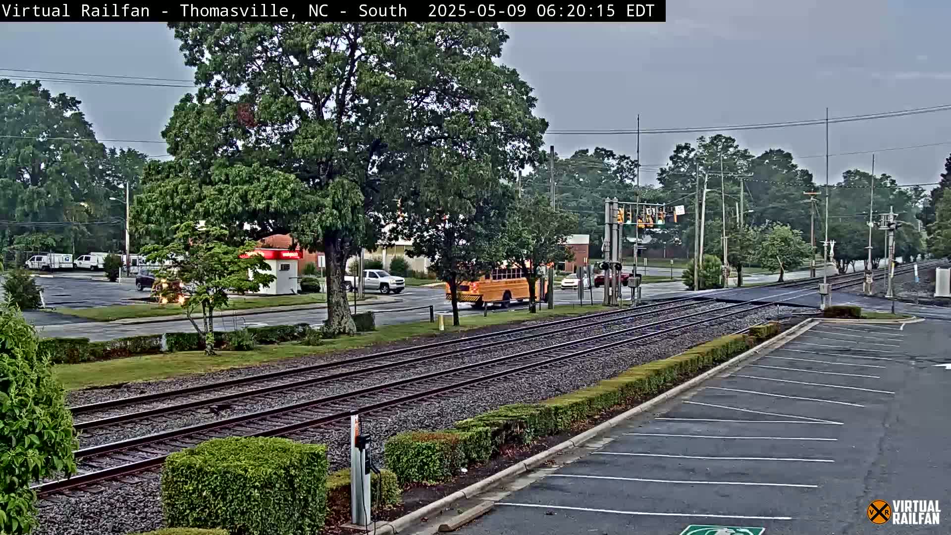 A school bus and several cars are seen near a railroad crossing on an overcast day.