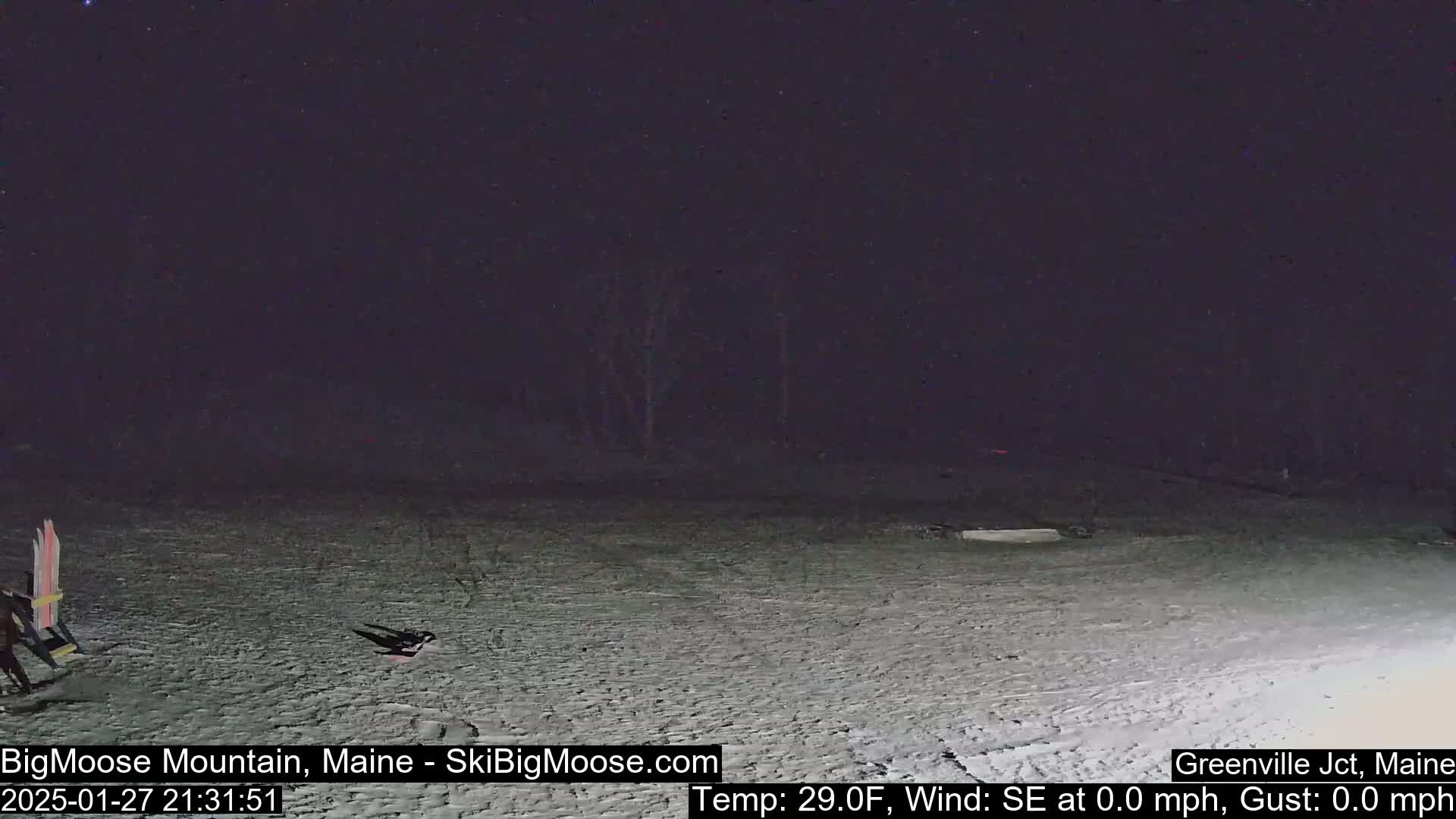 A snow-covered area at night with a calm wind, under a dark sky, shows some equipment and possibly a person lying on the ground.