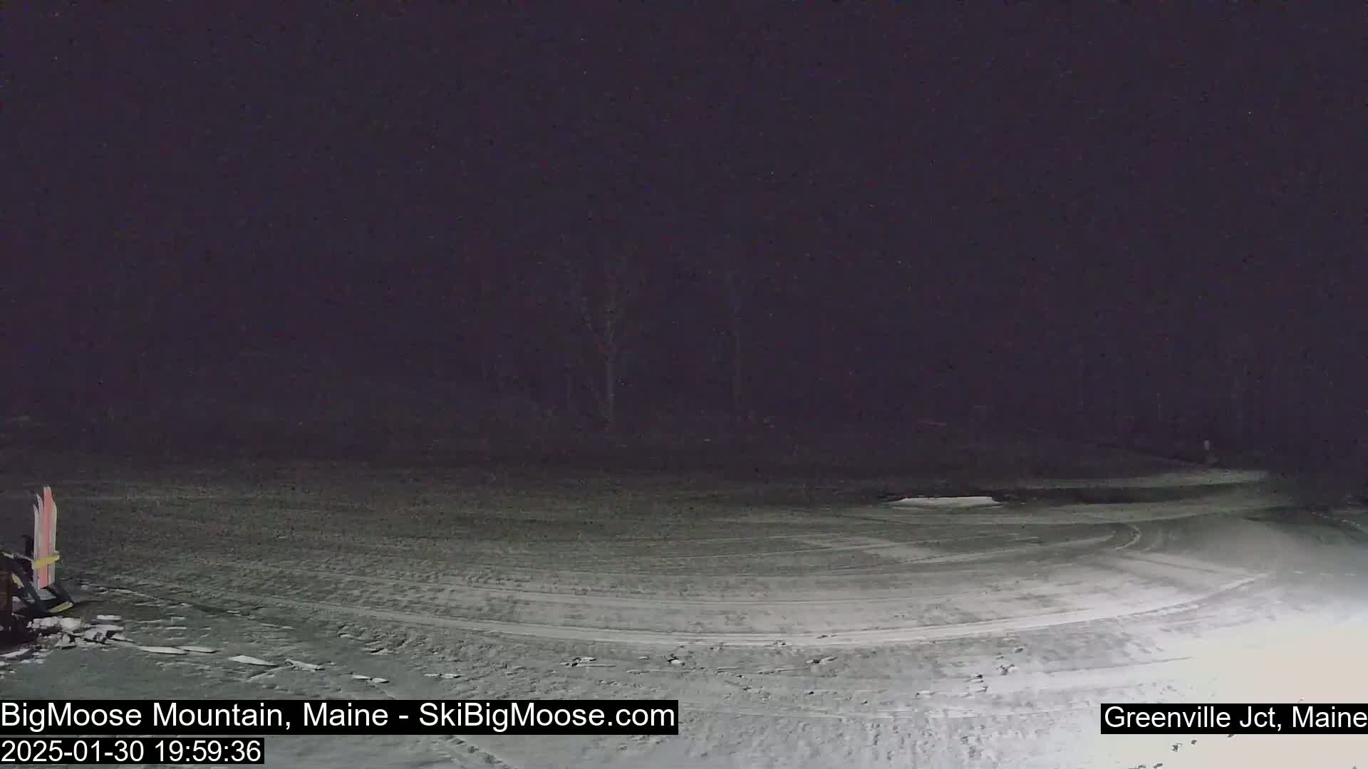 A snow-covered, empty parking lot is visible at night, under dark skies.
