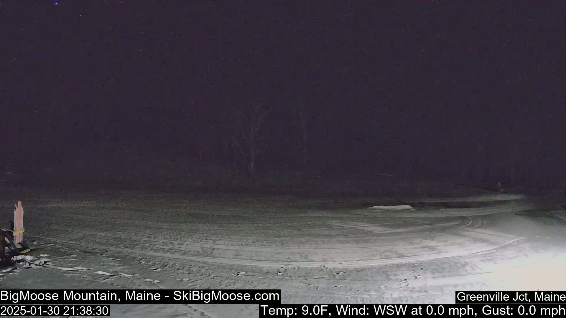 A snow-covered, empty parking lot is visible at night under a dark sky.