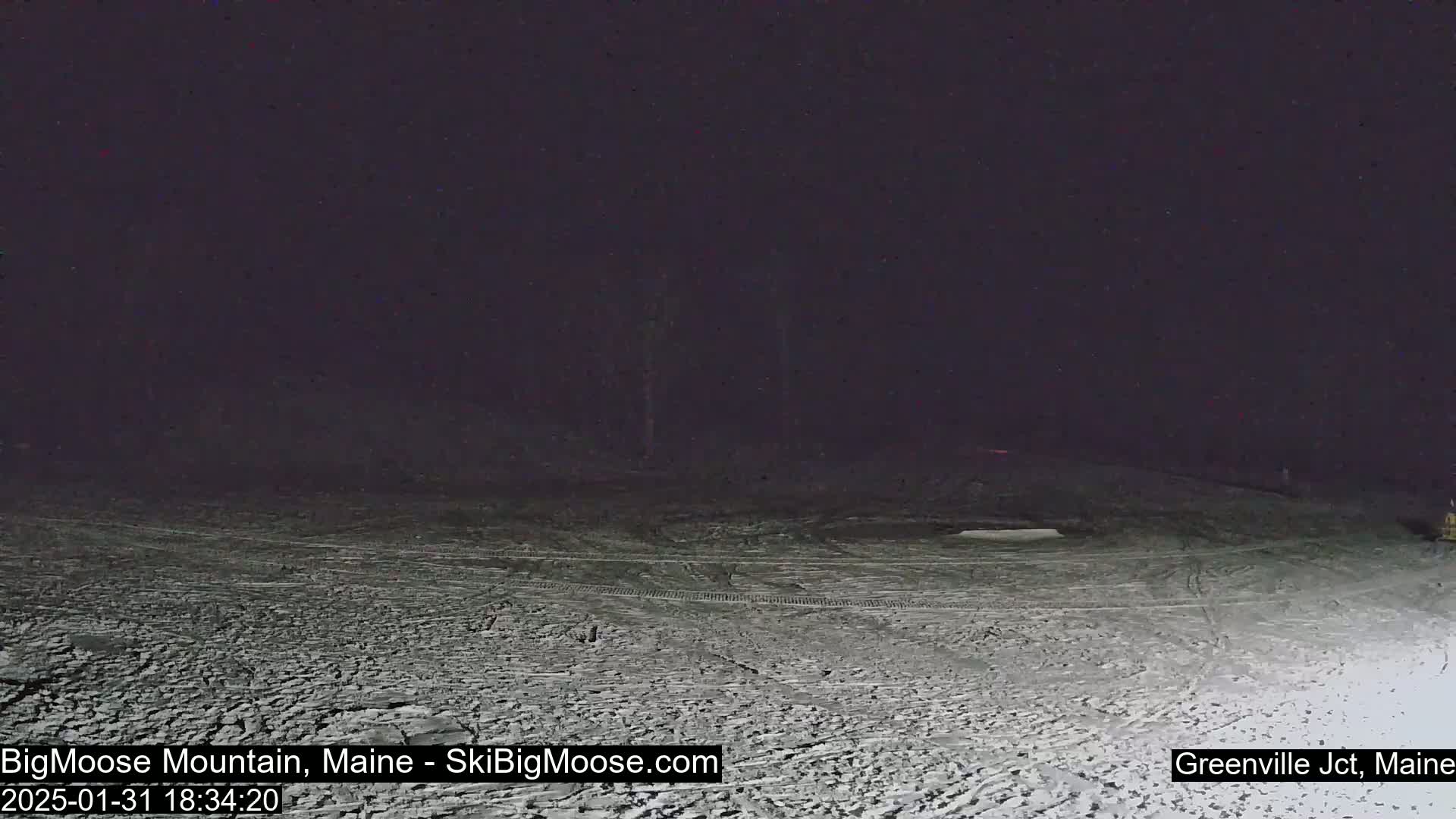 A snow-covered field is visible under a dark night sky.