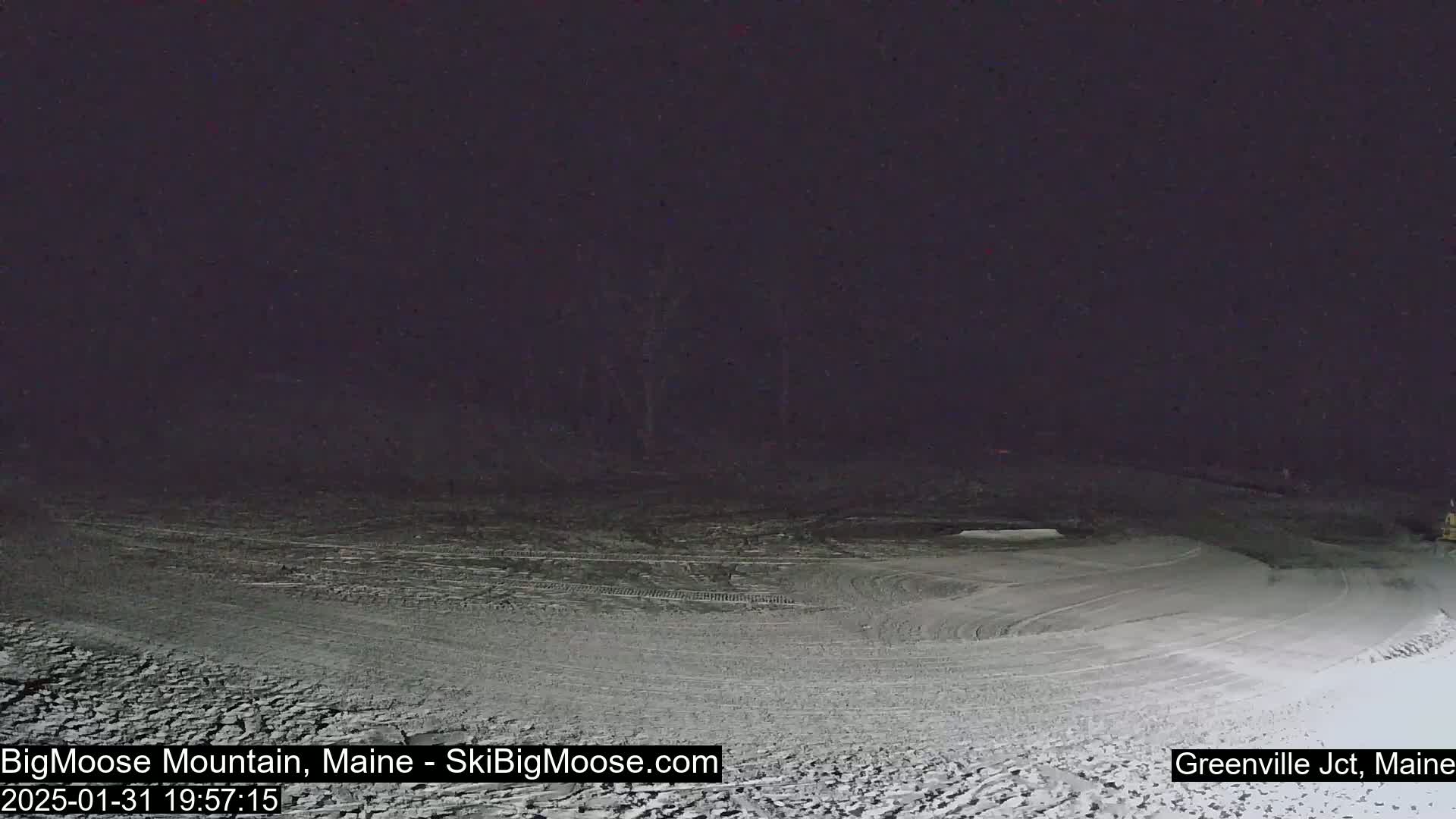 A snow-covered, circular area is illuminated at night under a dark sky.