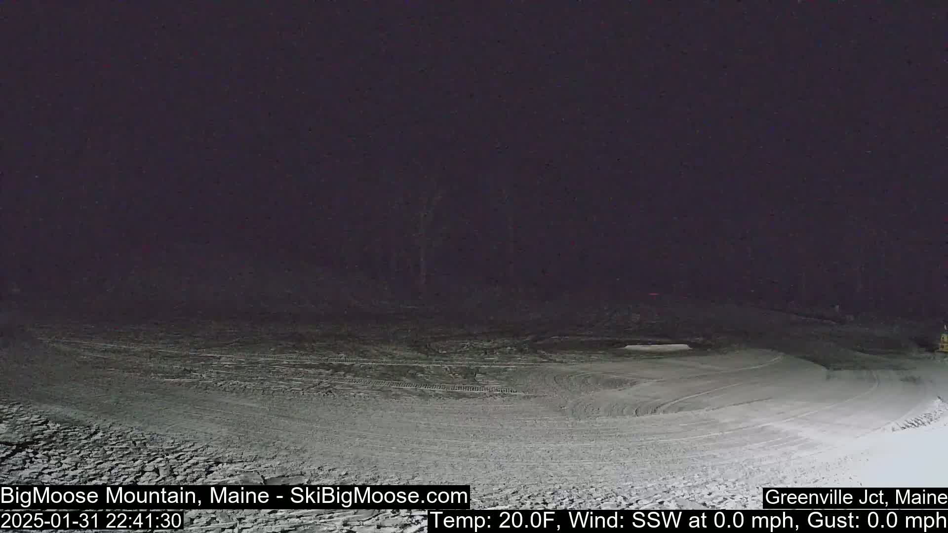 A snow-covered slope is visible at night under a dark sky.