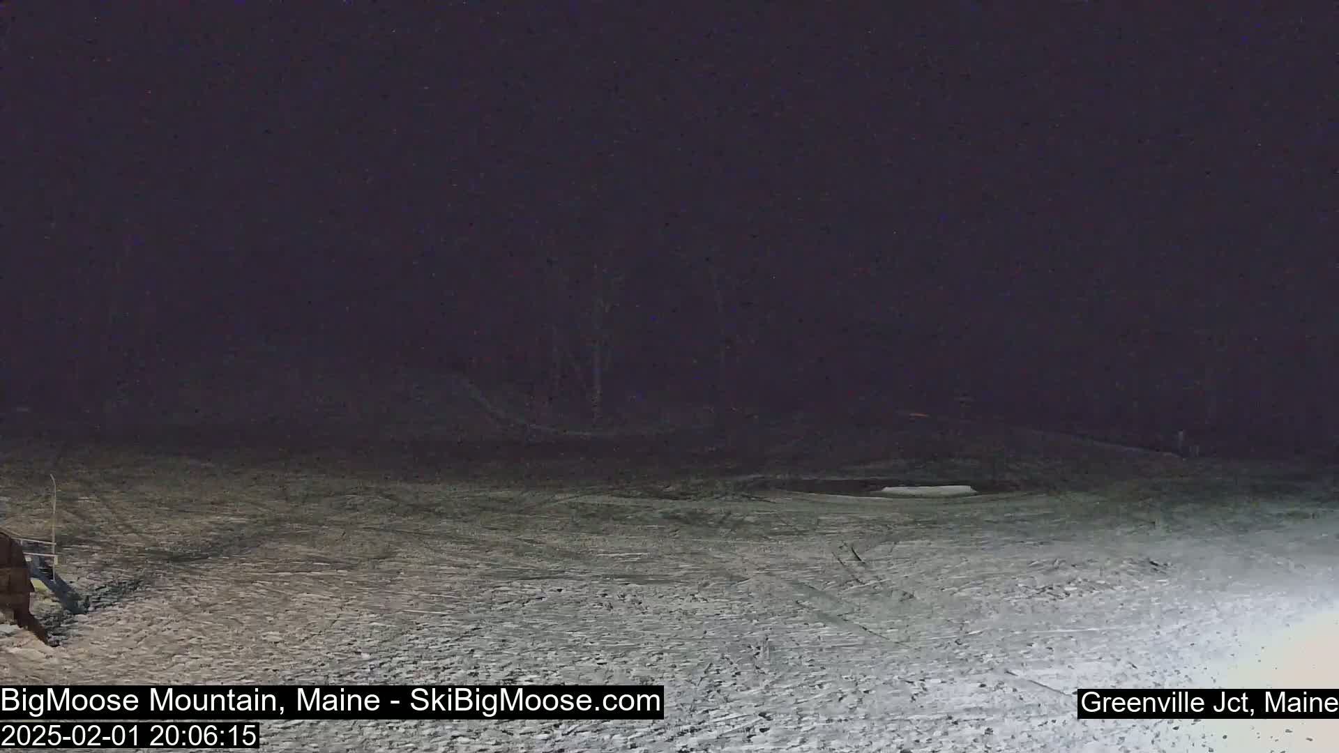 A snow-covered slope is visible at night under a dark sky.